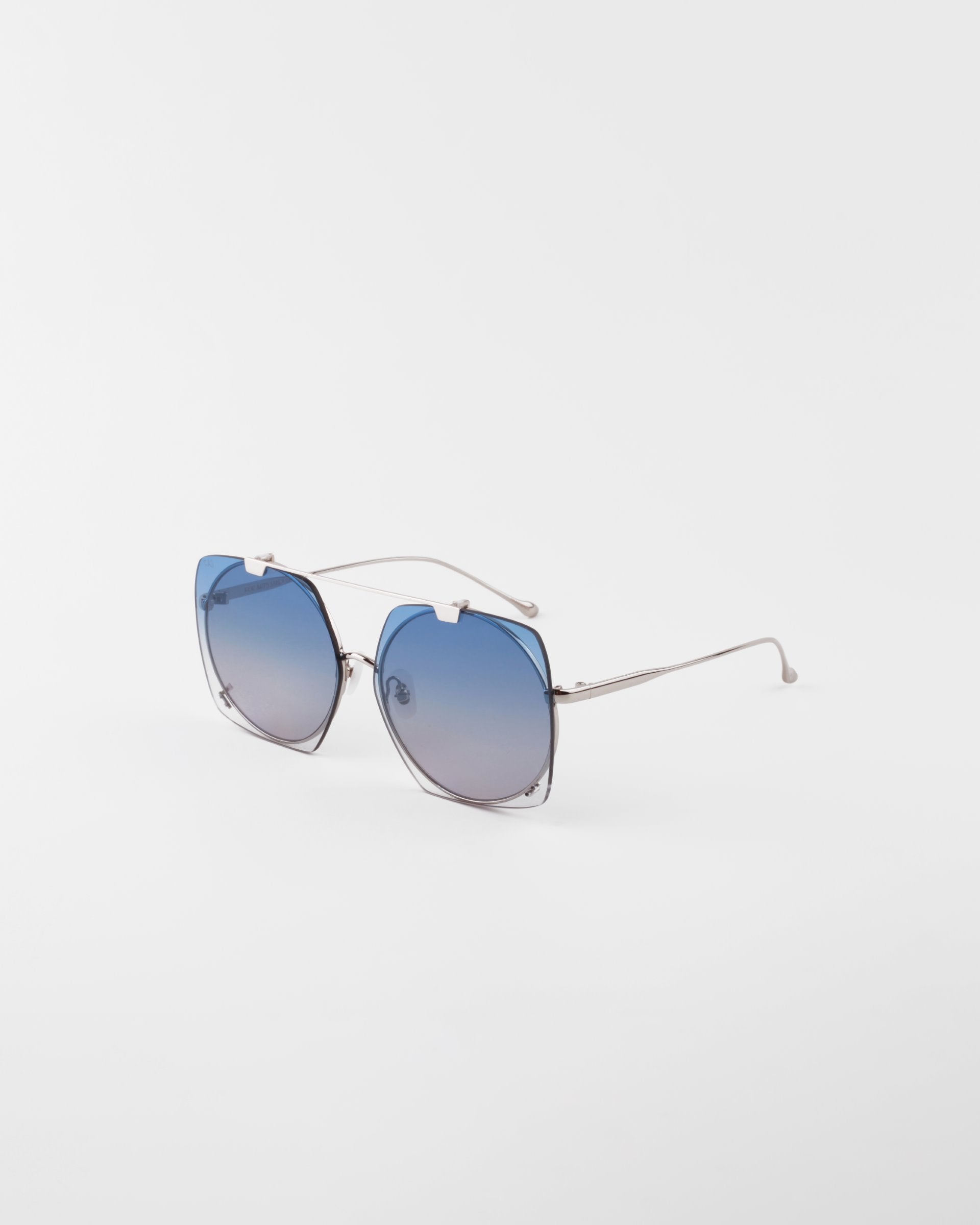 A pair of stylish, oversized Last Summer sunglasses by For Art&#39;s Sake® with blue gradient lenses and thin, 18-karat gold-plated metallic arms positioned on a white background.