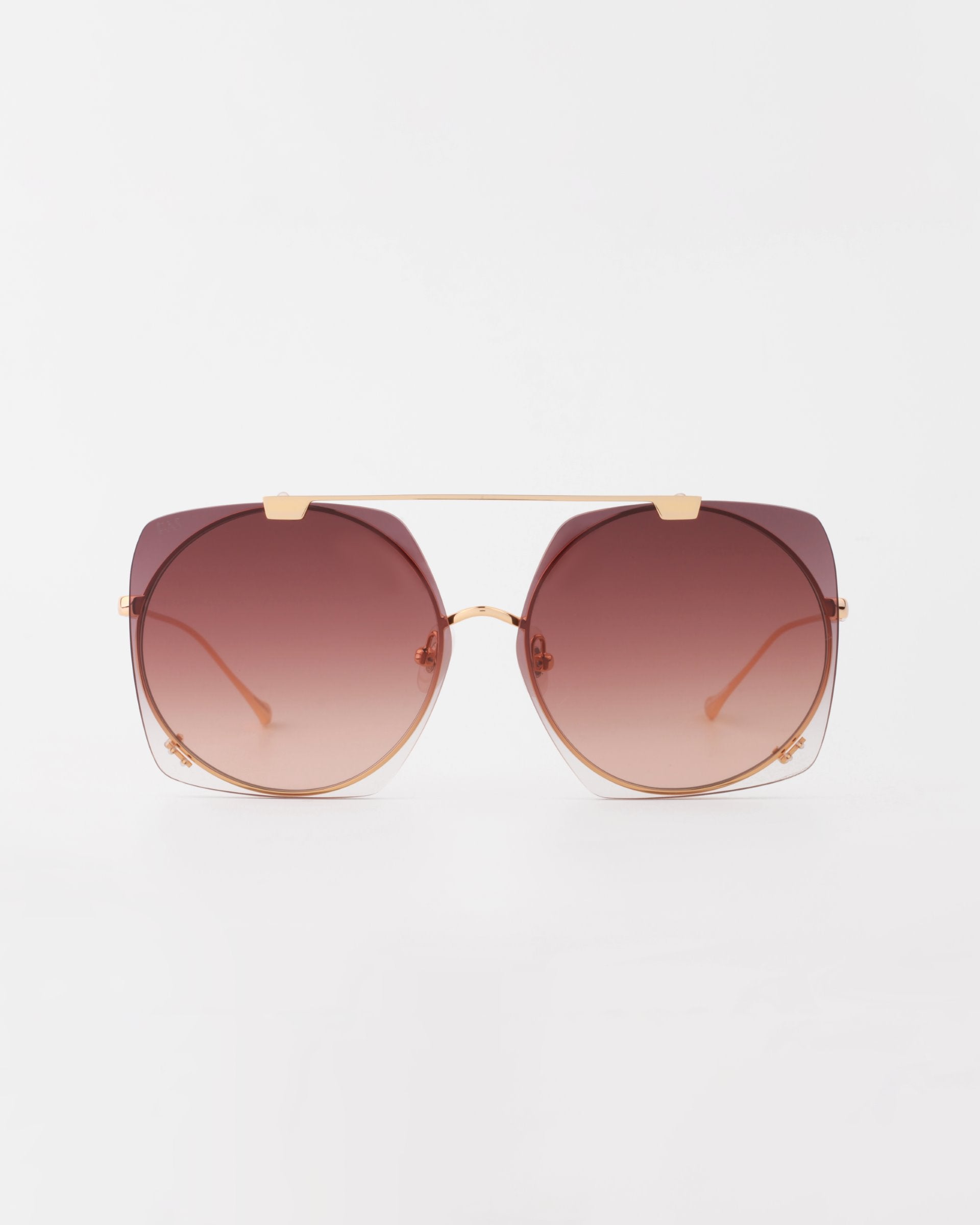 A pair of stylish sunglasses with oversized, round gradient lenses that transition from dark burgundy at the top to lighter at the bottom. The 18-karat gold-plated metal frame includes a thin bar across the top connecting the two sides, and the UVA & UVB-protected lenses are slightly angular. For Art's Sake® Last Summer.