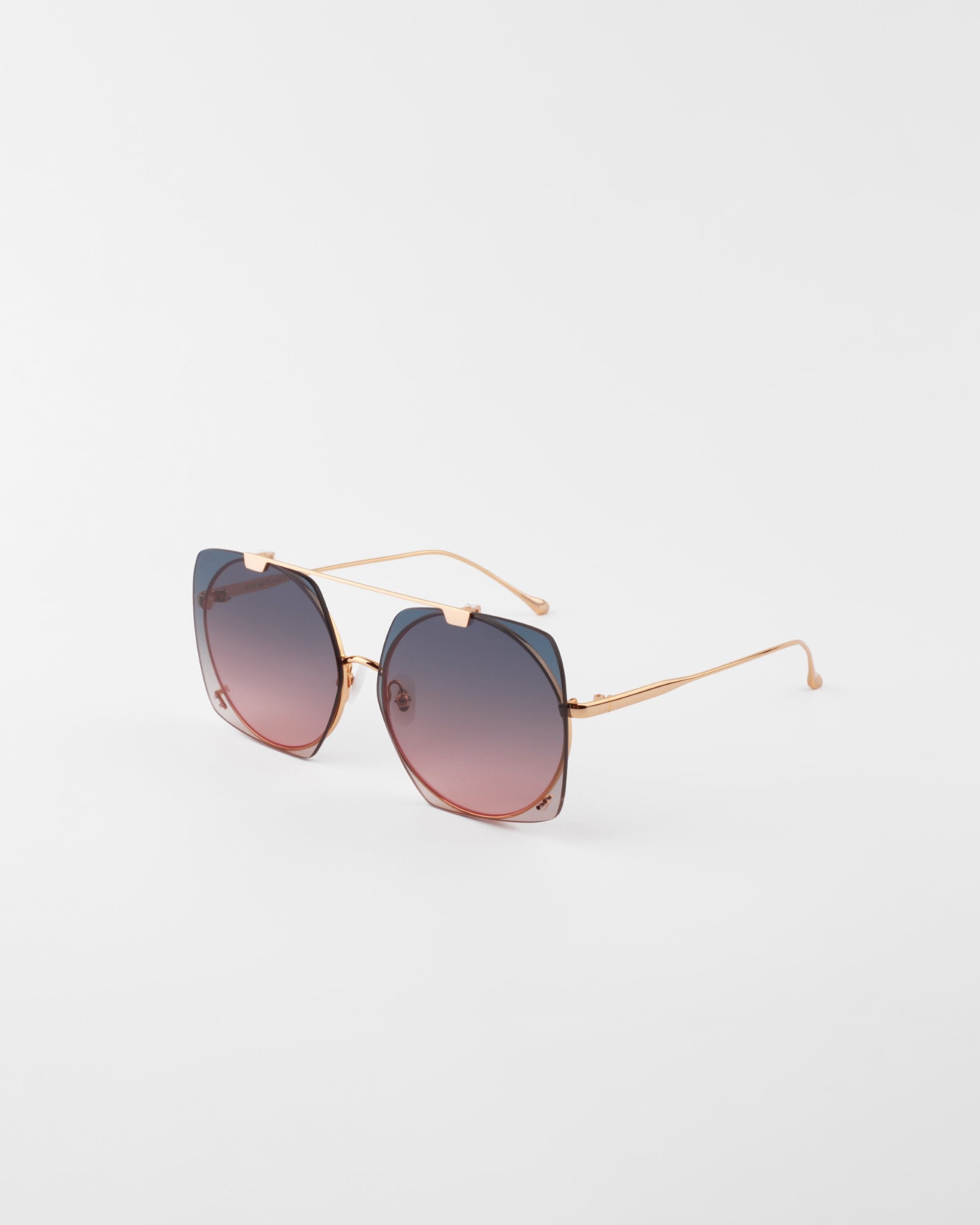 A pair of stylish For Art&#39;s Sake® Last Summer, 18-karat gold-plated sunglasses with thin frames and gradient lenses that transition from dark at the top to lighter at the bottom. The UVA &amp; UVB-protected lenses have a subtle cat-eye shape. The sunglasses are set against a plain white background.