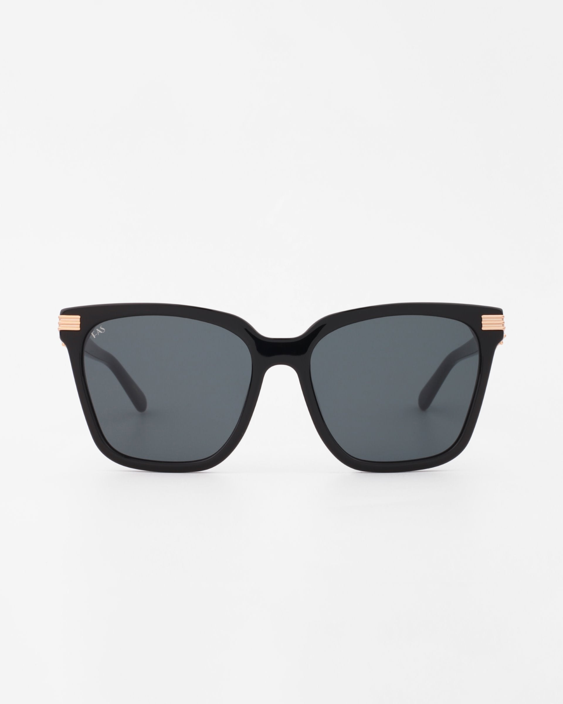 A pair of black square-framed Gaia sunglasses with dark, UV-protected lenses. The slightly thick, minimalist handmade acetate frames feature 18-karat gold-plated accents near the hinges. The background is plain white. For Art's Sake®.