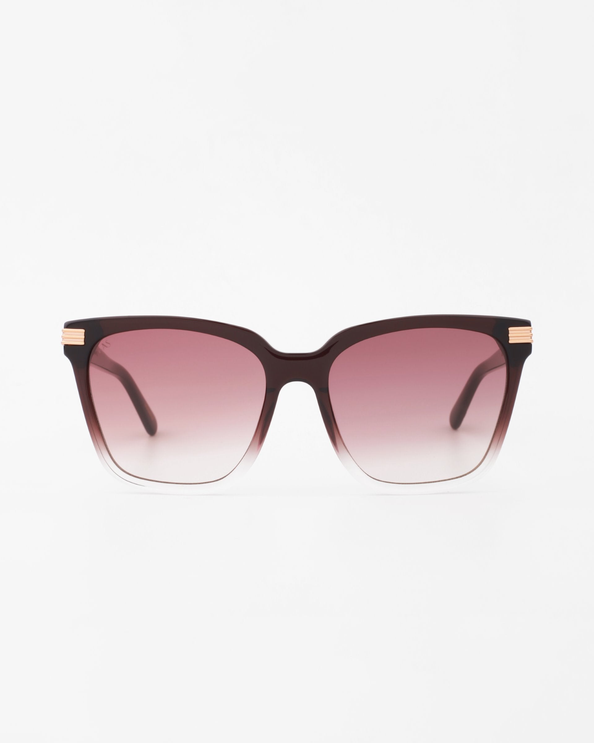 A pair of rectangular, oversized, handmade acetate sunglasses with a gradient frame that transitions from dark brown at the top to clear at the bottom. The UV-protected lenses fade from dark pink at the top to light pink at the bottom. The arms feature 18-karat gold-plated accents near the hinges. These are Gaia by For Art's Sake®.