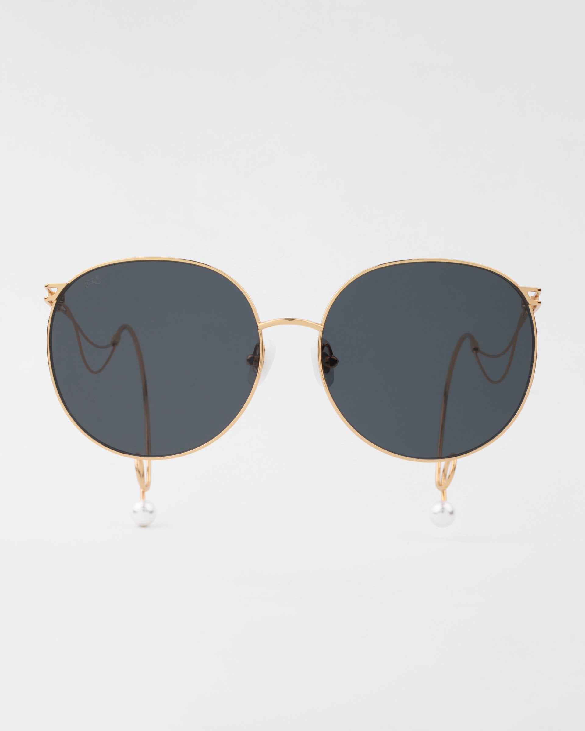 A pair of stylish sunglasses with round, dark, lightweight shatter-resistant lenses and a thin, gold metal frame. The temples feature gold chains with pearl ends attached, hanging down on each side. These Birthday Cake sunglasses by For Art's Sake® are set against a plain white background.