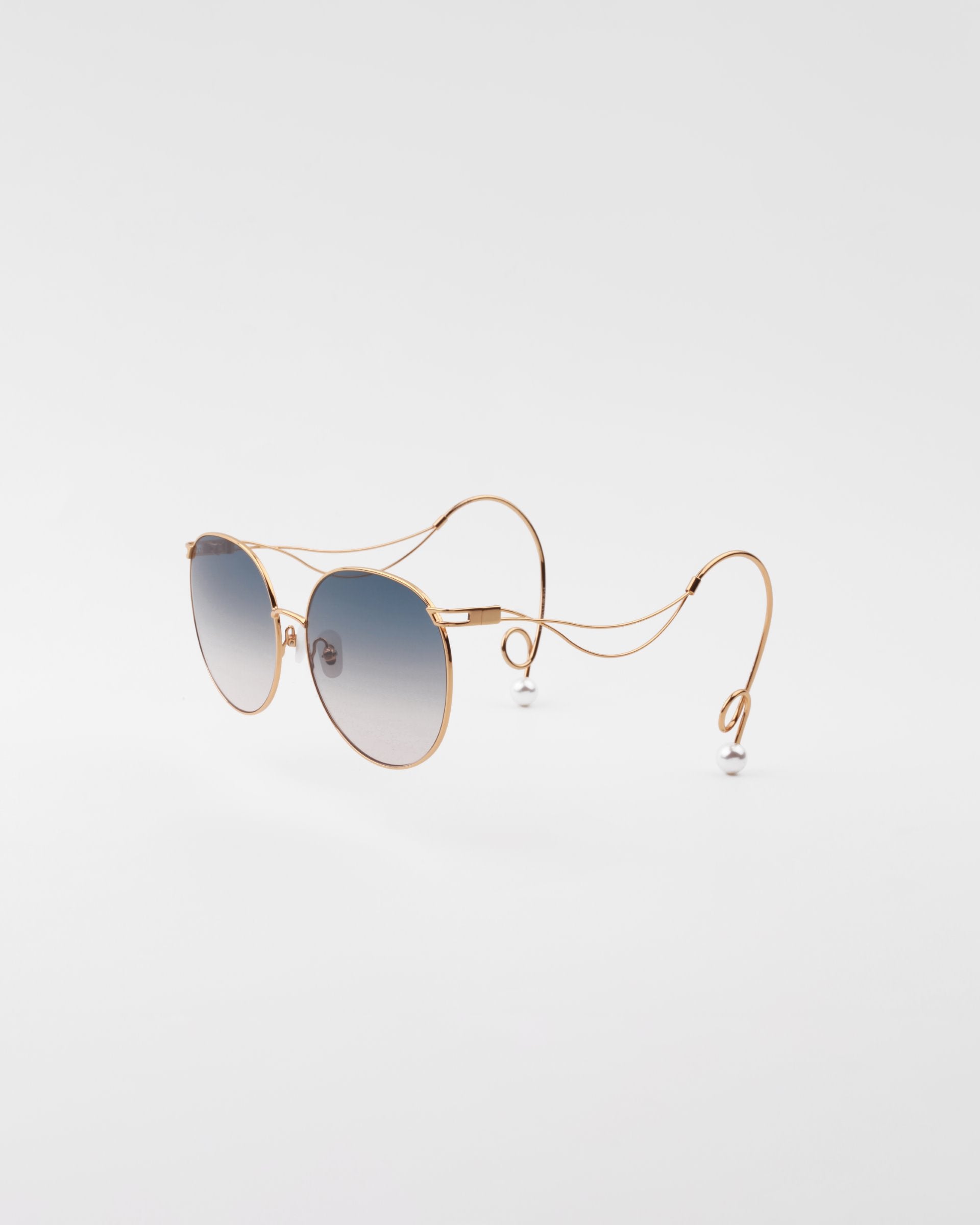A pair of sunglasses featuring round, lightweight shatter-resistant lenses with a gradient from dark to light shades. The handmade gold-plated frame has thin, intricate wire temples that curve and loop at the ends, with hypoallergenic nose pads adding comfort to this unique and stylish Birthday Cake design by For Art's Sake® against a plain white background.