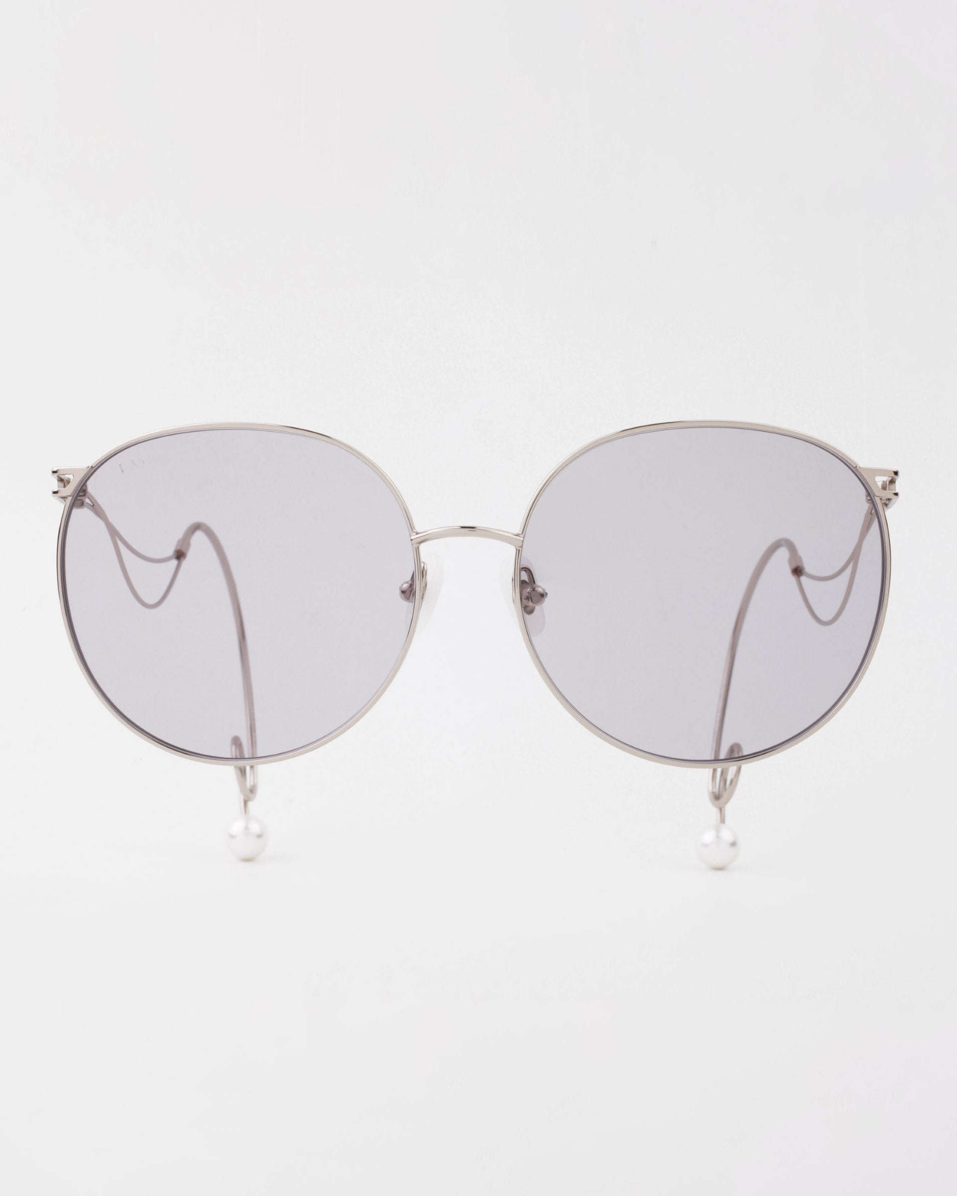 A pair of For Art&#39;s Sake® Birthday Cake silver-framed sunglasses with round, dark-tinted lenses. The temples feature a unique design with looped wire and small, pearl-like accents at the tips. Lightweight shatter-resistant lenses ensure durability and comfort. The background is plain white.