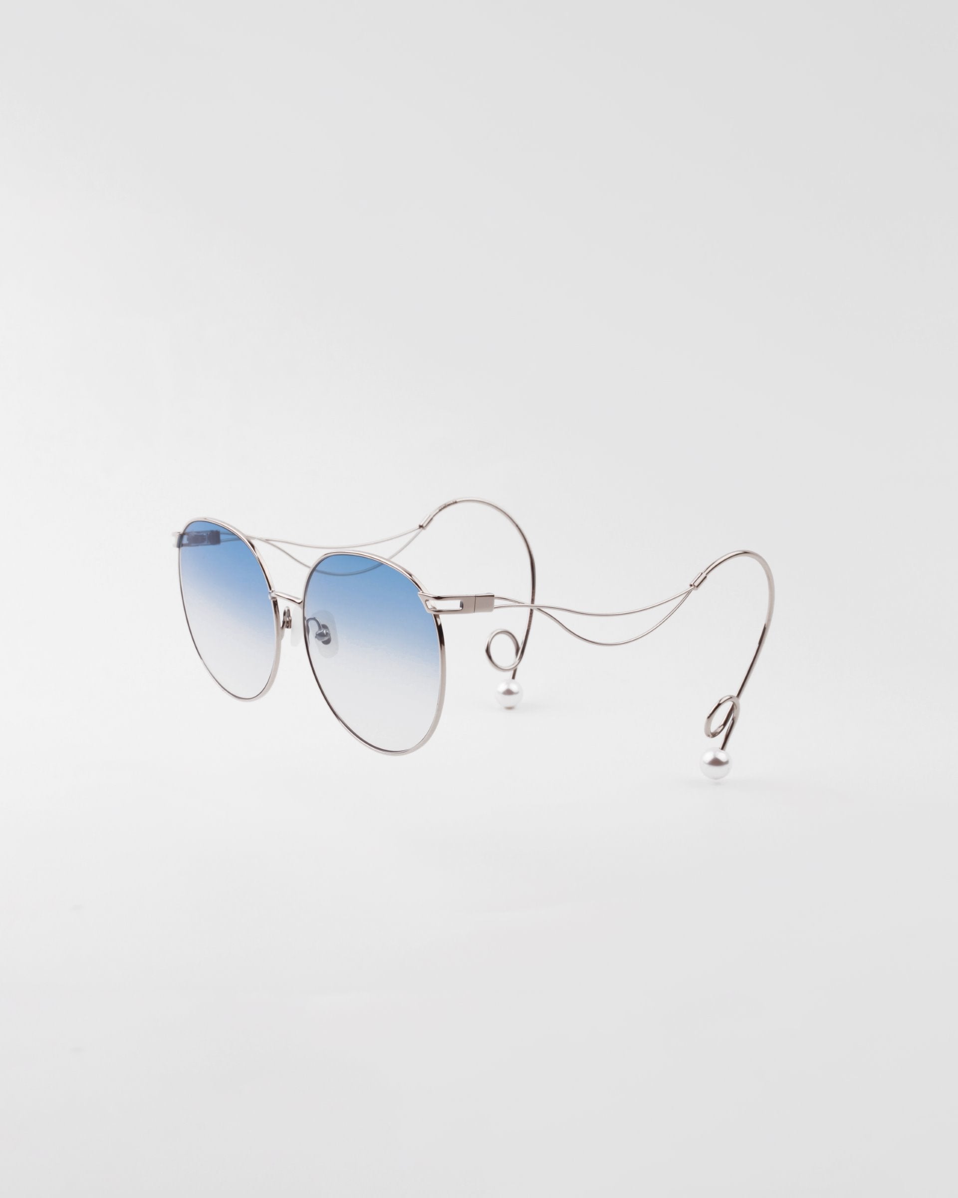 A pair of round sunglasses featuring handcrafted gold-plated frames and blue gradient, shatter-resistant lenses. The arms have an intricate, looping design that adds a unique and stylish touch. Hypoallergenic nose pads ensure comfort. The background is plain white. This is the Birthday Cake by For Art&#39;s Sake®.