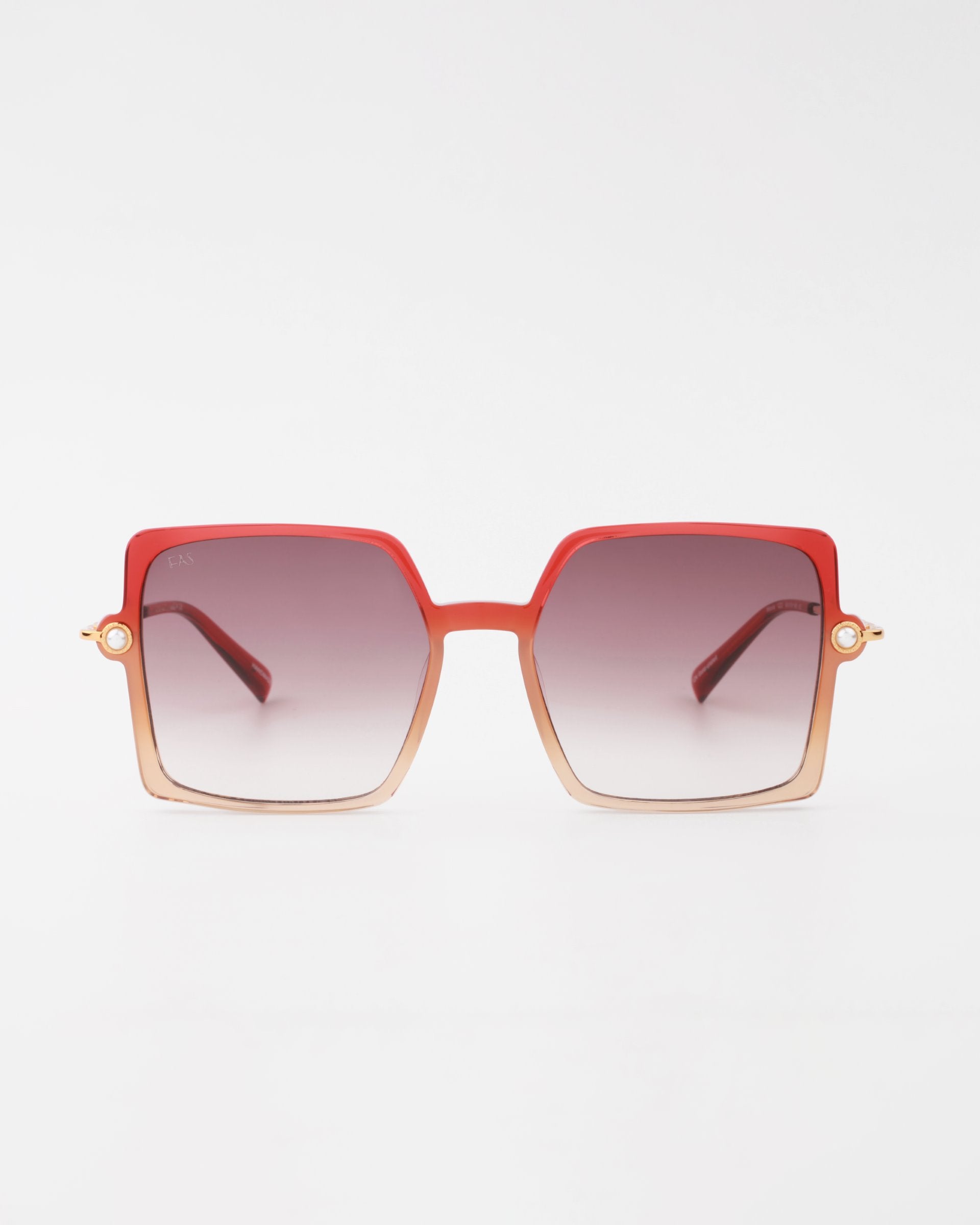 A pair of stylish handmade acetate For Art's Sake® Moxie sunglasses with large, gradient square lenses that transition from dark gray at the top to lighter shades towards the bottom. The frames are ombre, blending from red to a lighter tan hue with 18-karat gold-plated arms and offering full UVA & UVB protection.