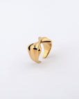 The Sydney Ring by For Art's Sake® is a polished gold-plated piece featuring a modern, sculptural design with an asymmetrical twisted form against a plain white background. The smooth and reflective surface of this ring highlights its elegant and contemporary style, subtly reminiscent of a bow-shaped design.