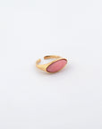 Introducing the Enza Ring by For Art's Sake®: a gold-plated stainless steel piece featuring a pink, oval-shaped stone setting. The band is adjustable with a smooth, polished enamel finish. Displayed on a plain white background, this ring exudes elegance and versatility.