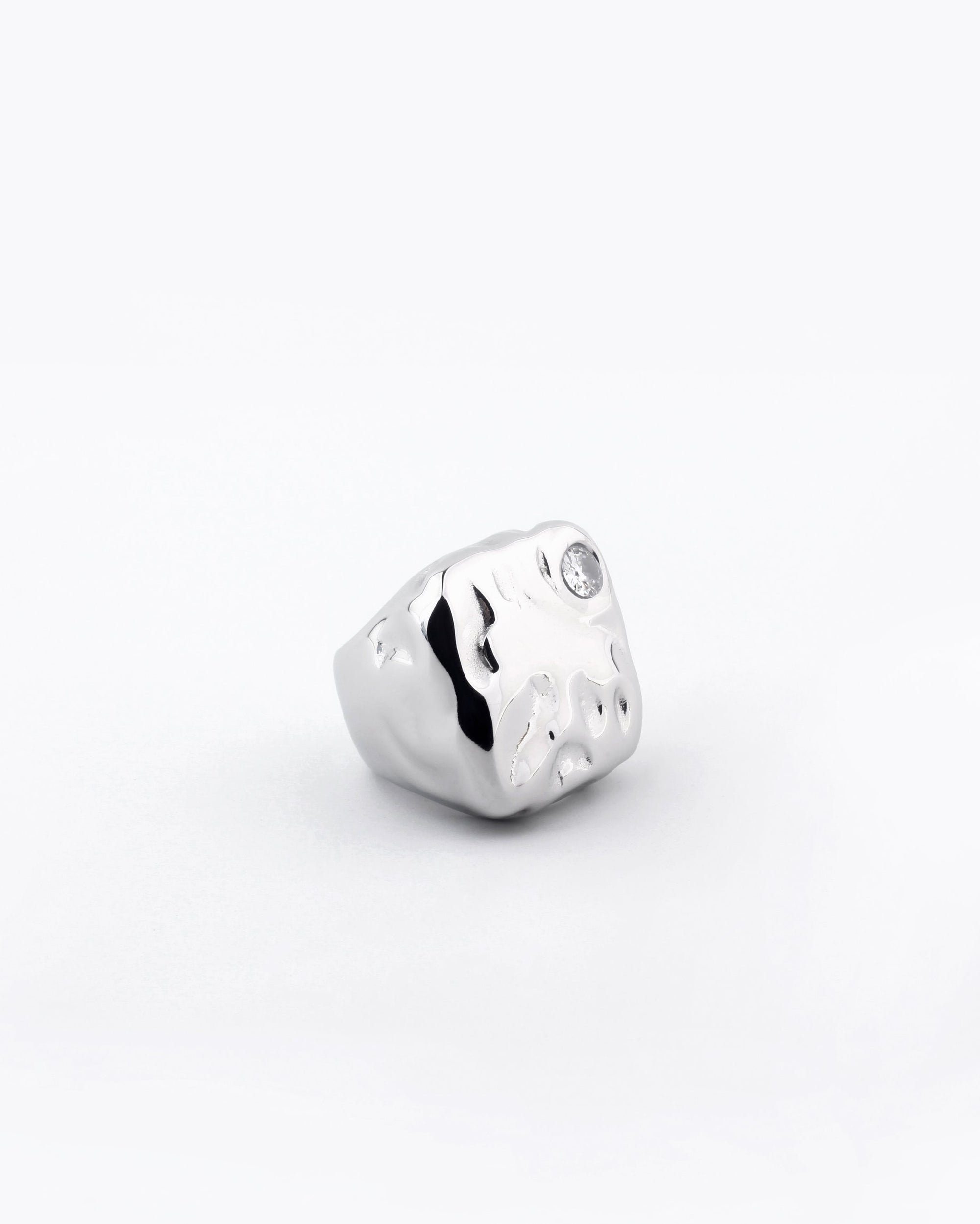 A chunky Chiara Ring by For Art&#39;s Sake® features a silver-plated, textured organic design with a small round gemstone embedded near one edge, all set against a clean white background.