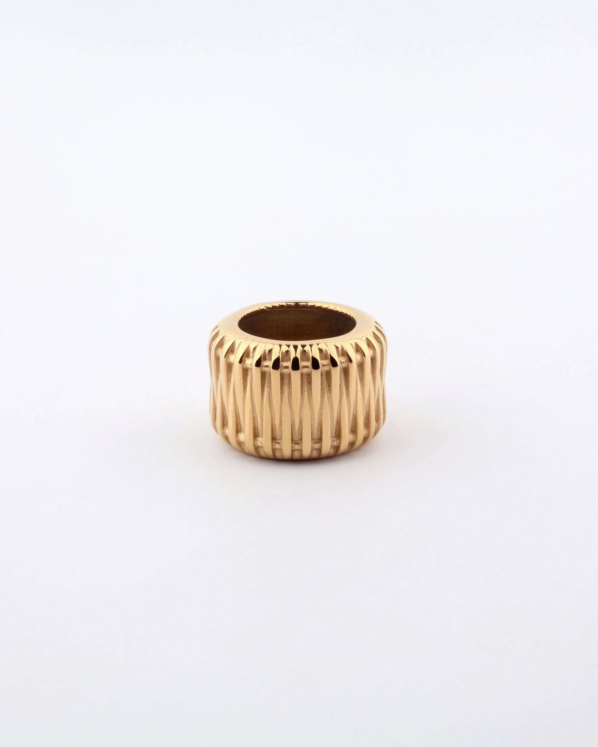 A gold Metallic Woven Ring by For Art&#39;s Sake® with an 18kt gold-plated, ribbed design is placed centrally against a white background. The ring features a cylindrical shape with a hollow center.