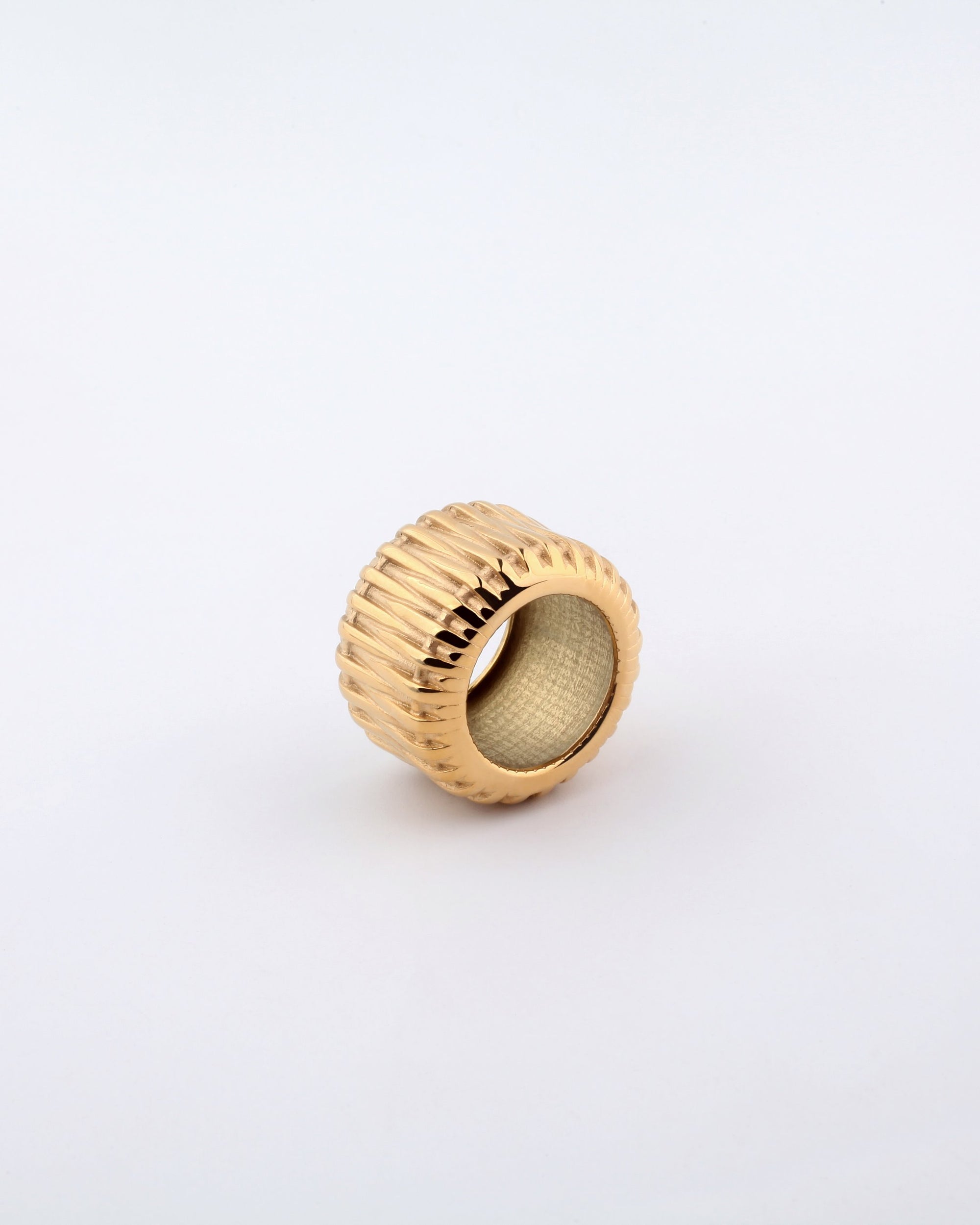 A Woven Ring by For Art's Sake®, gold-plated with a woven design and ribbed texture on the outside and a smooth inner surface, stands upright against a plain white background.