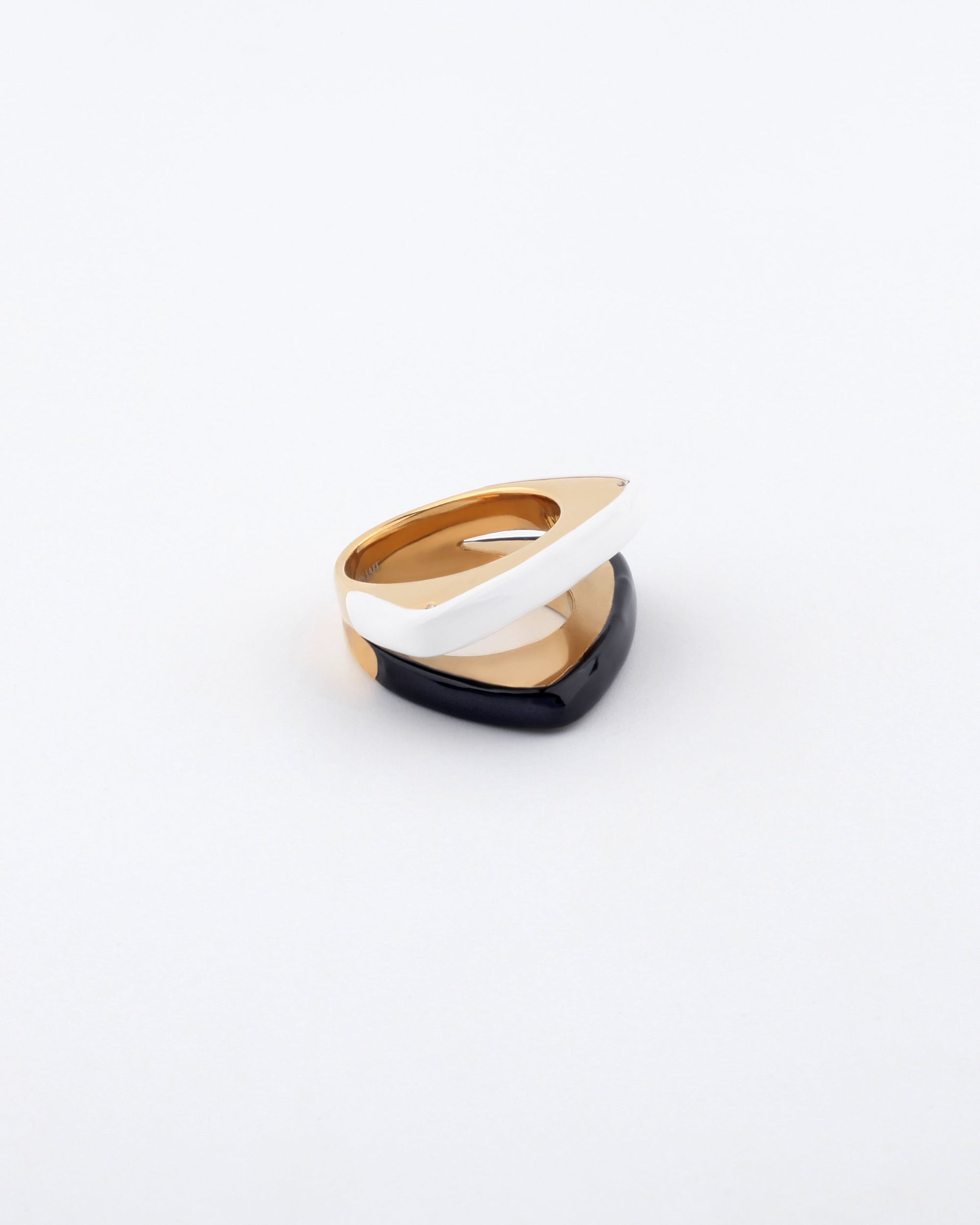 The Delta Ring by For Art&#39;s Sake® features a modern, geometric design with two interlocking pieces—one black and one white—set against a plain white background. The ring exudes a sleek and contemporary aesthetic, appearing to be crafted from polished metal or ceramic to create a sophisticated, layered design.