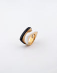 A stylish Delta Ring by For Art's Sake®, showcasing a distinctive layered design with a chic black and white contrasting color scheme. The ring exudes a modern aesthetic with its smooth, curvy shapes seamlessly blending into a polished gold base, beautifully set against a plain white backdrop.