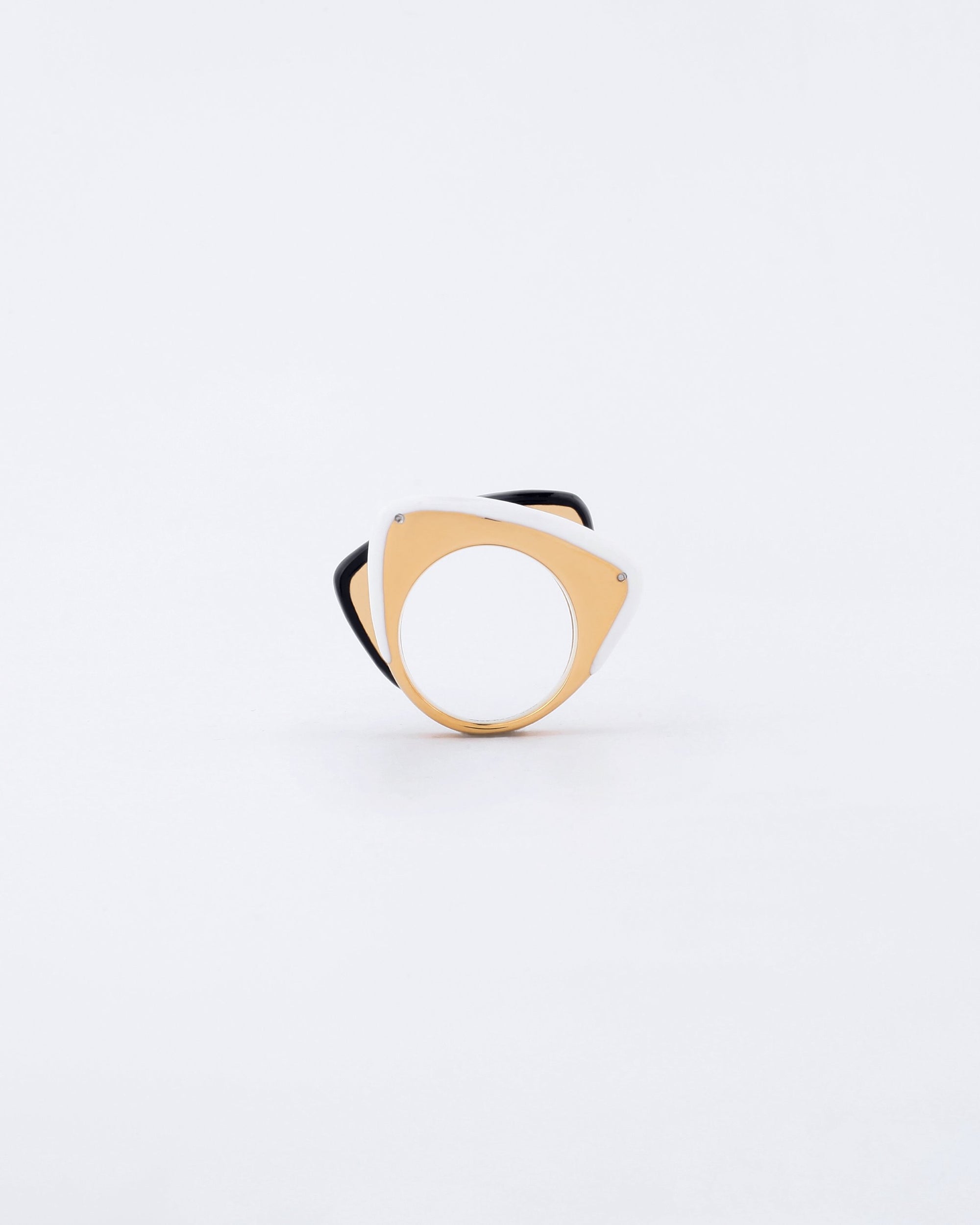 The Delta Ring by For Art's Sake®, a minimalist, modern piece with a geometric design, is showcased against a plain white background. It features a triangular shape with rounded edges, combining silver and gold tones and boasts a unique layered design accentuated by a bold splash of color along its inner side.