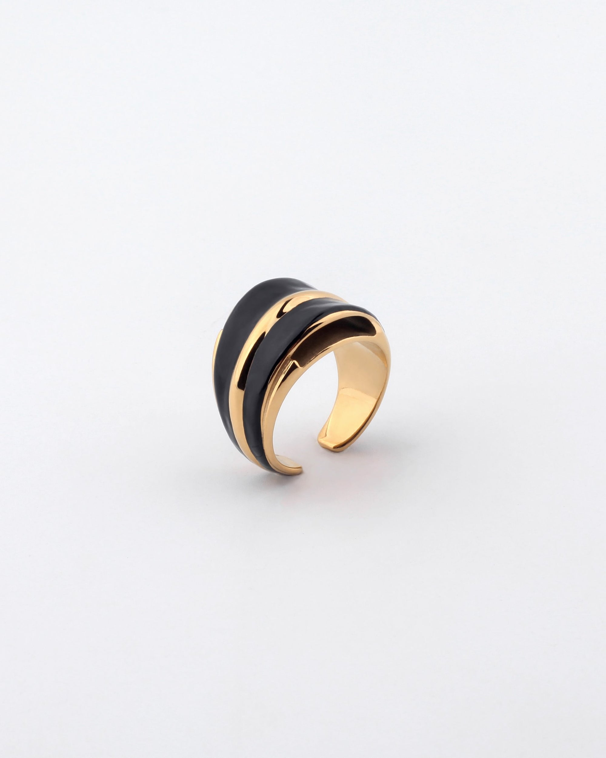 Introducing the Maven Ring by For Art's Sake®—a trendy gold open-ended ring featuring a sleek, black, wave-like design running through its center. This elegant piece exudes a modern, minimalist aesthetic and is showcased against a plain, light-colored background.