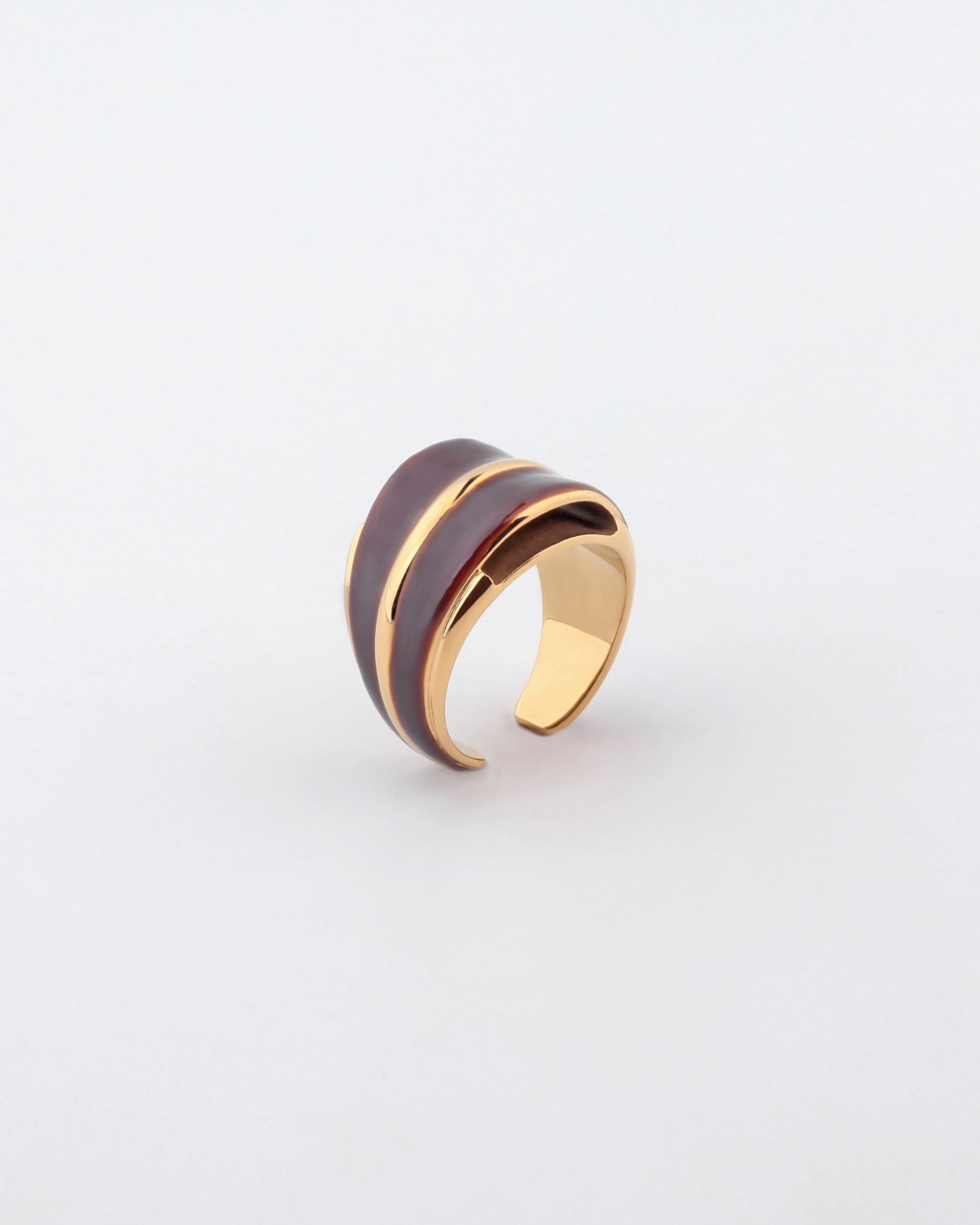 For Art&#39;s Sake® presents the Maven Ring, featuring a wide band with a sleek design. The exterior boasts a smooth, dark brown finish accented by gold-toned metal, creating a stylish contrast with the gold interior. The ring is showcased against a plain, light background.