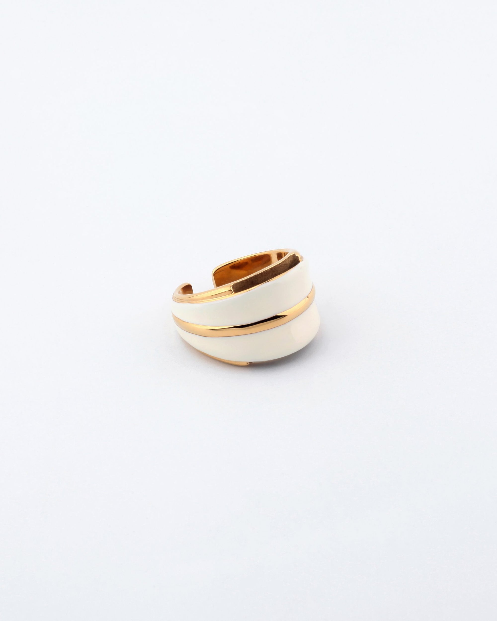 The Maven Ring from For Art's Sake® is an elegant jewelry piece with an overlapping band design. Featuring a smooth finish and sections of white enamel contrasted by gold-toned accents, it offers a stylish and contemporary look. The plain white background accentuates its exquisite details perfectly.