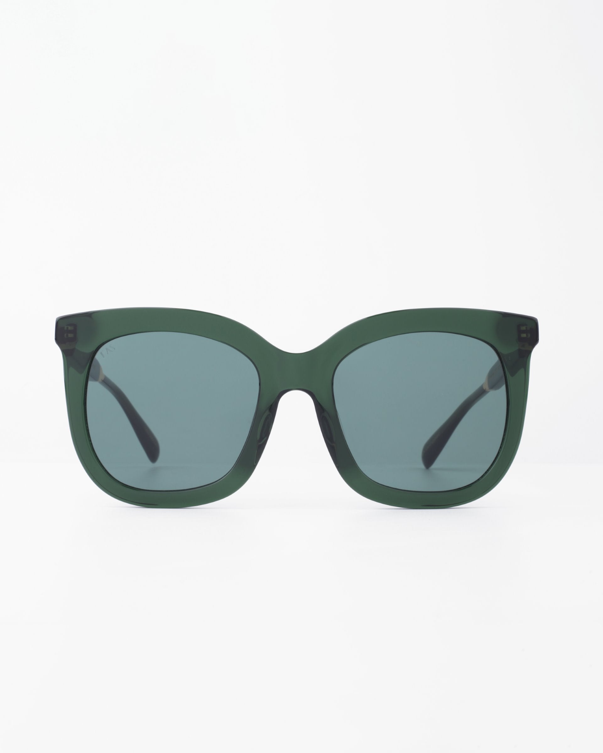 A pair of dark green, rectangular Riverside sunglasses by For Art&#39;s Sake® with slightly curved edges and shatter-resistant dark lenses, displayed against a plain white background. The handmade acetate frame features black temples that are slightly visible from this frontal view.