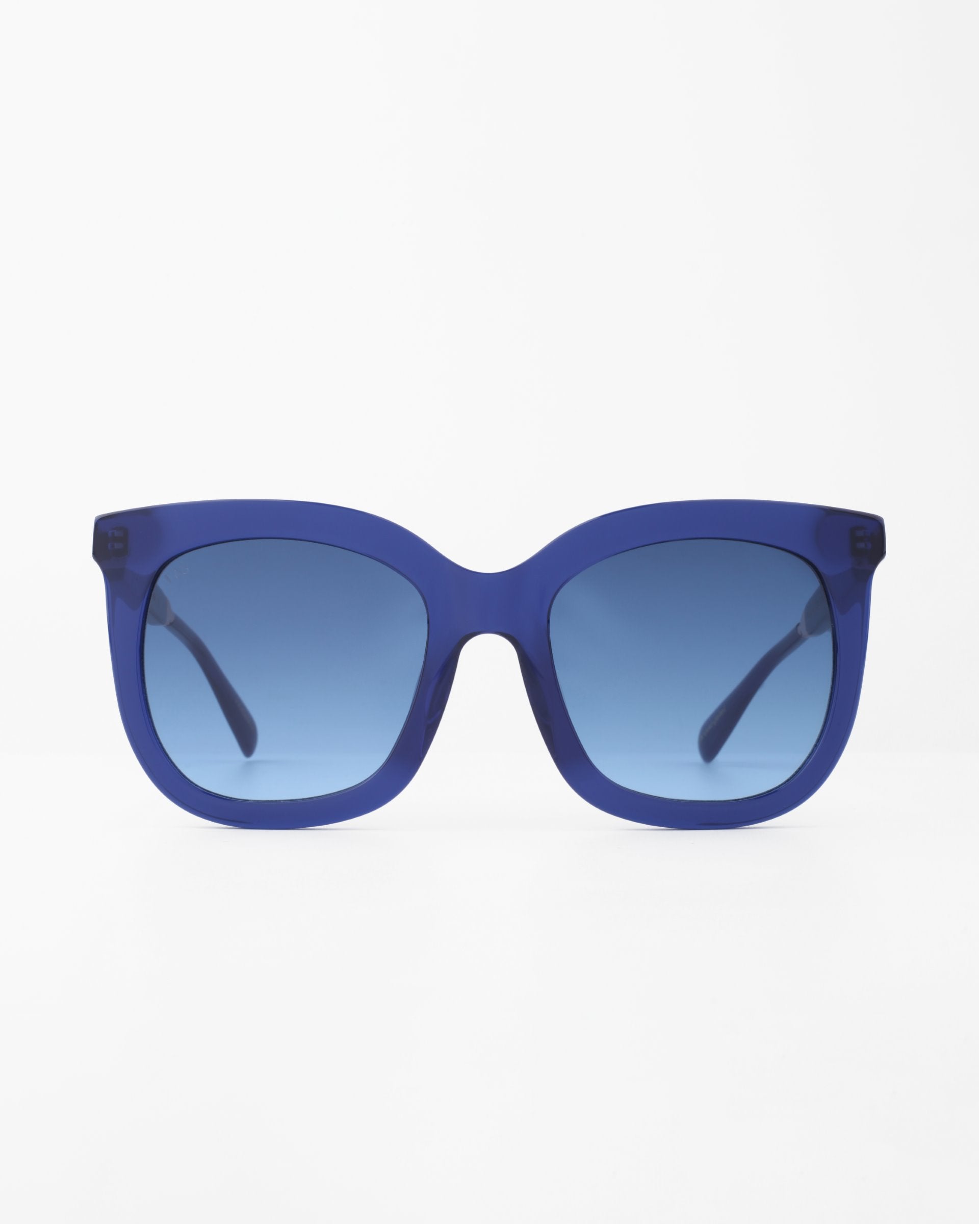 A pair of For Art's Sake® Riverside square-shaped sunglasses with a blue frame and blue-tinted, shatter-resistant lenses is centered against a white background. The sunglasses have a minimalist and modern design.