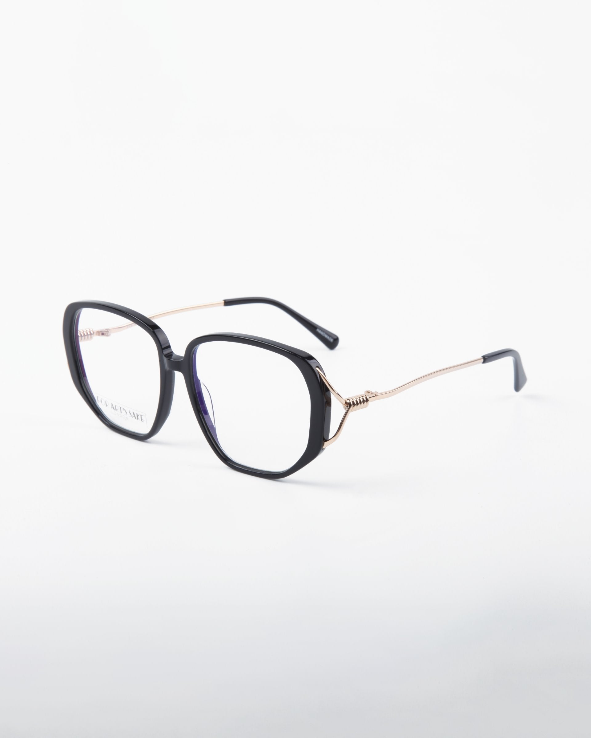A pair of stylish For Art&#39;s Sake® Remix prescription eyeglasses with large black square frames and thin gold arms. The arms are decorated with a small coil detail near the hinges, and the glasses have transparent lenses with UV protection. The background is white.