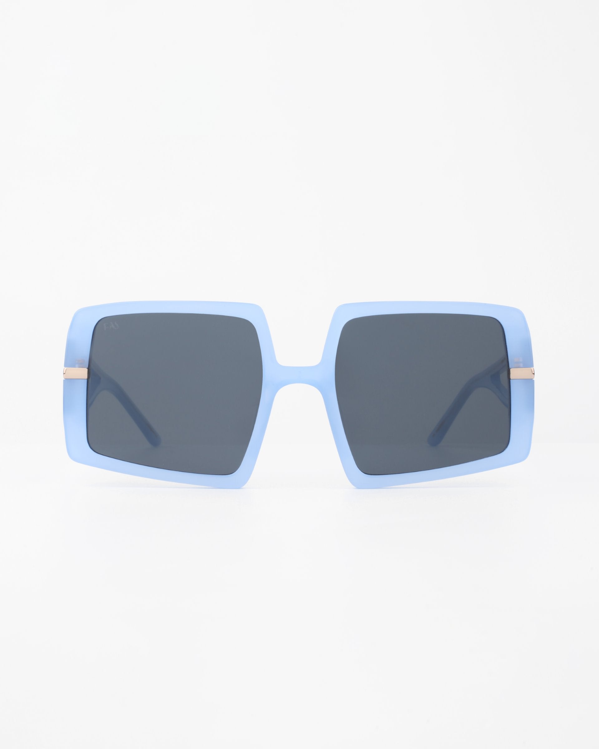 A pair of oversized rectangular For Art's Sake® Saturday sunglasses with light blue, plant-based acetate frames and dark, shatter-resistant nylon lenses positioned against a white background. The sunglasses have a bold, fashionable look with thick frames and slightly rounded edges.
