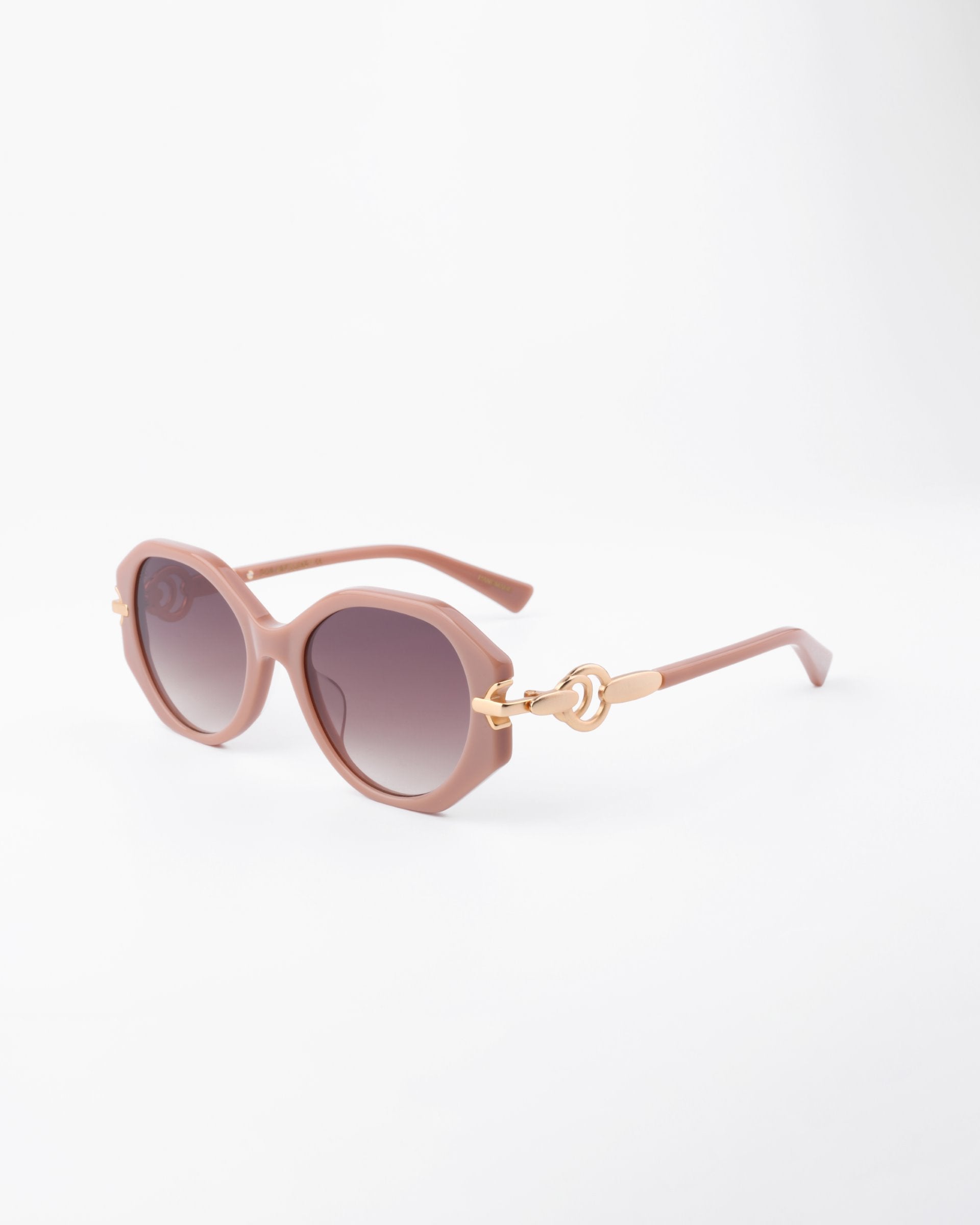 A pair of stylish round sunglasses with light pink, handmade acetate frames and gradient dark, shatter-resistant lenses. The arms feature gold-plated temple detailing near the hinges, adding a touch of elegance. The background is plain white, highlighting the Seaside by For Art&#39;s Sake®.