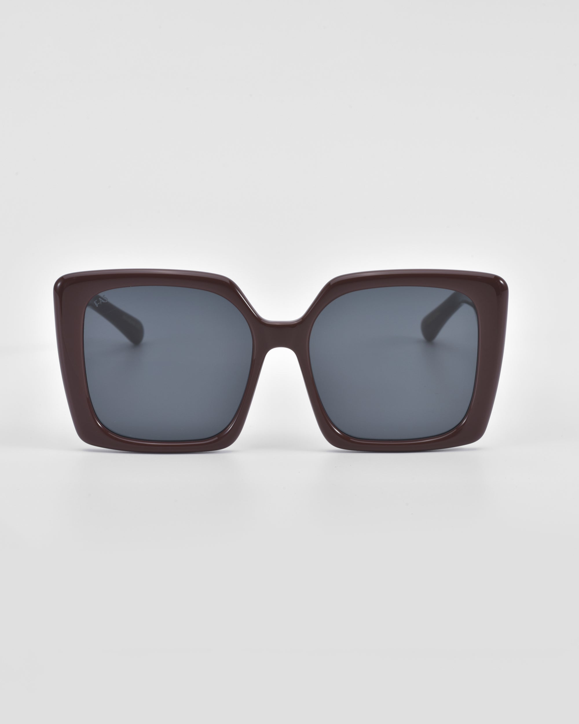 A pair of oversized soft-square For Art's Sake® Eos sunglasses with dark frames, viewed from the front against a plain white background. The lenses are tinted dark, providing a chic and fashionable appearance. Classic temple round details elevate the timeless charm, making these shades a stylish staple.