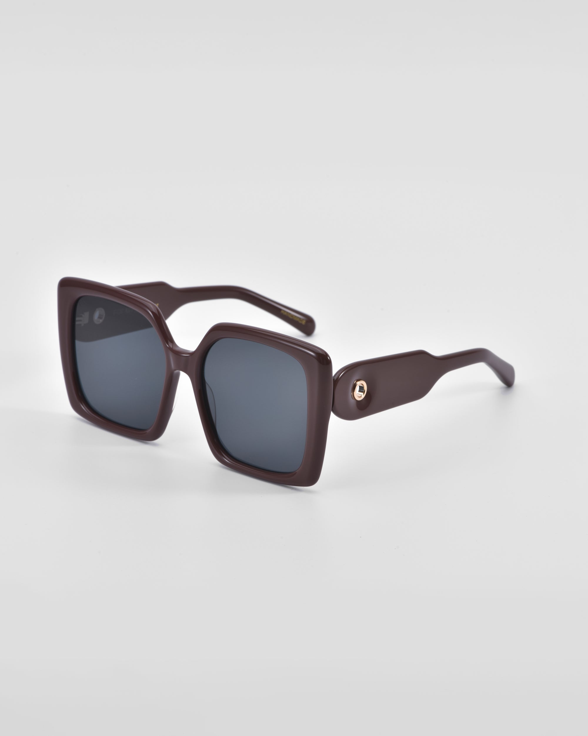 A pair of stylish, oversized, square-framed For Art&#39;s Sake® Eos sunglasses with dark lenses and thick, dark brown frames. The sunglasses are positioned against a plain white background, showcasing their design details clearly.