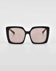 Front view of Eos oversized soft-square sunglasses by For Art's Sake® with black rims and pink-tinted lenses against a white background.