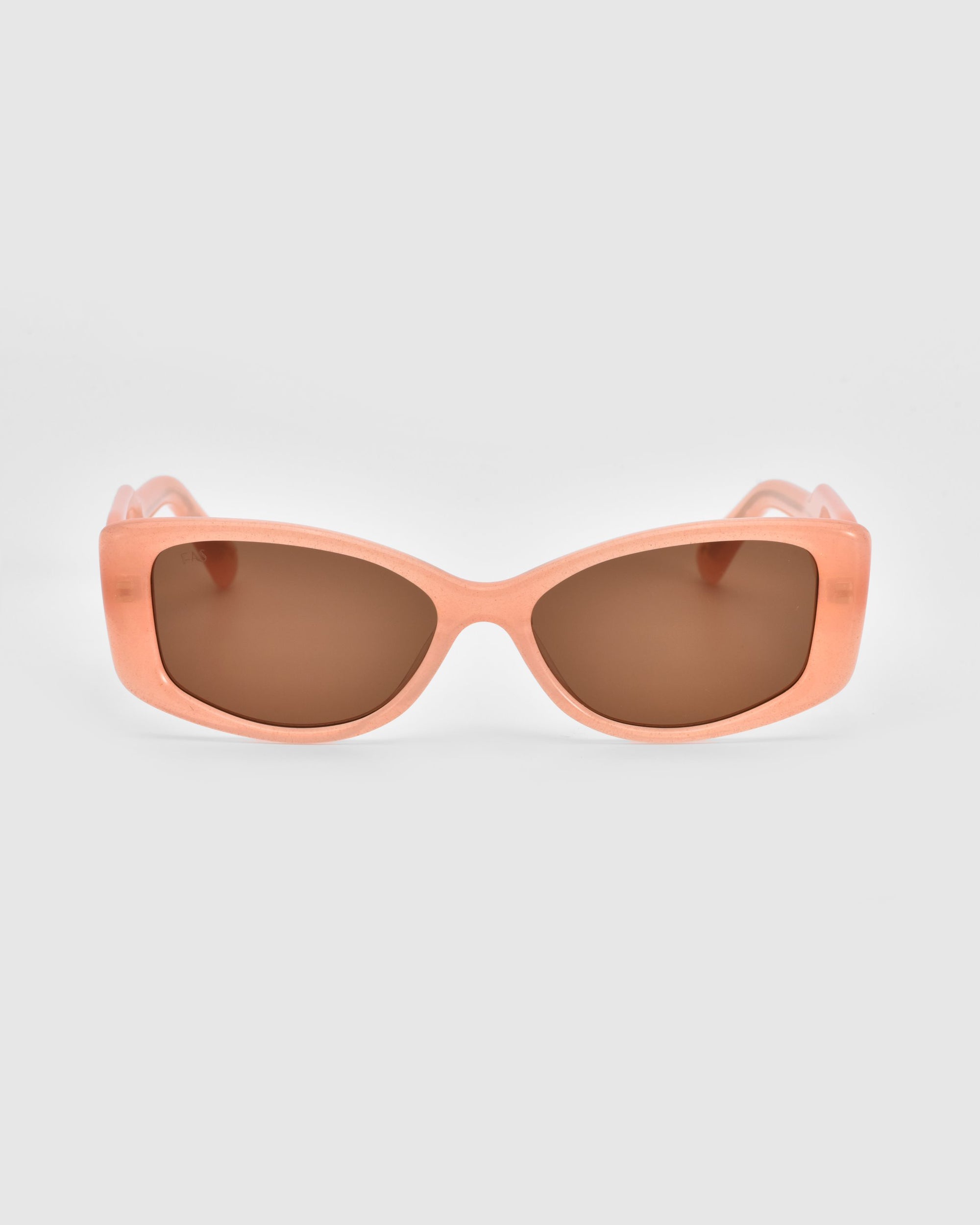 A pair of chic Mene cat-eye sunglasses by For Art&#39;s Sake® features peach-colored frames and brown tinted lenses, set on a light gray background.