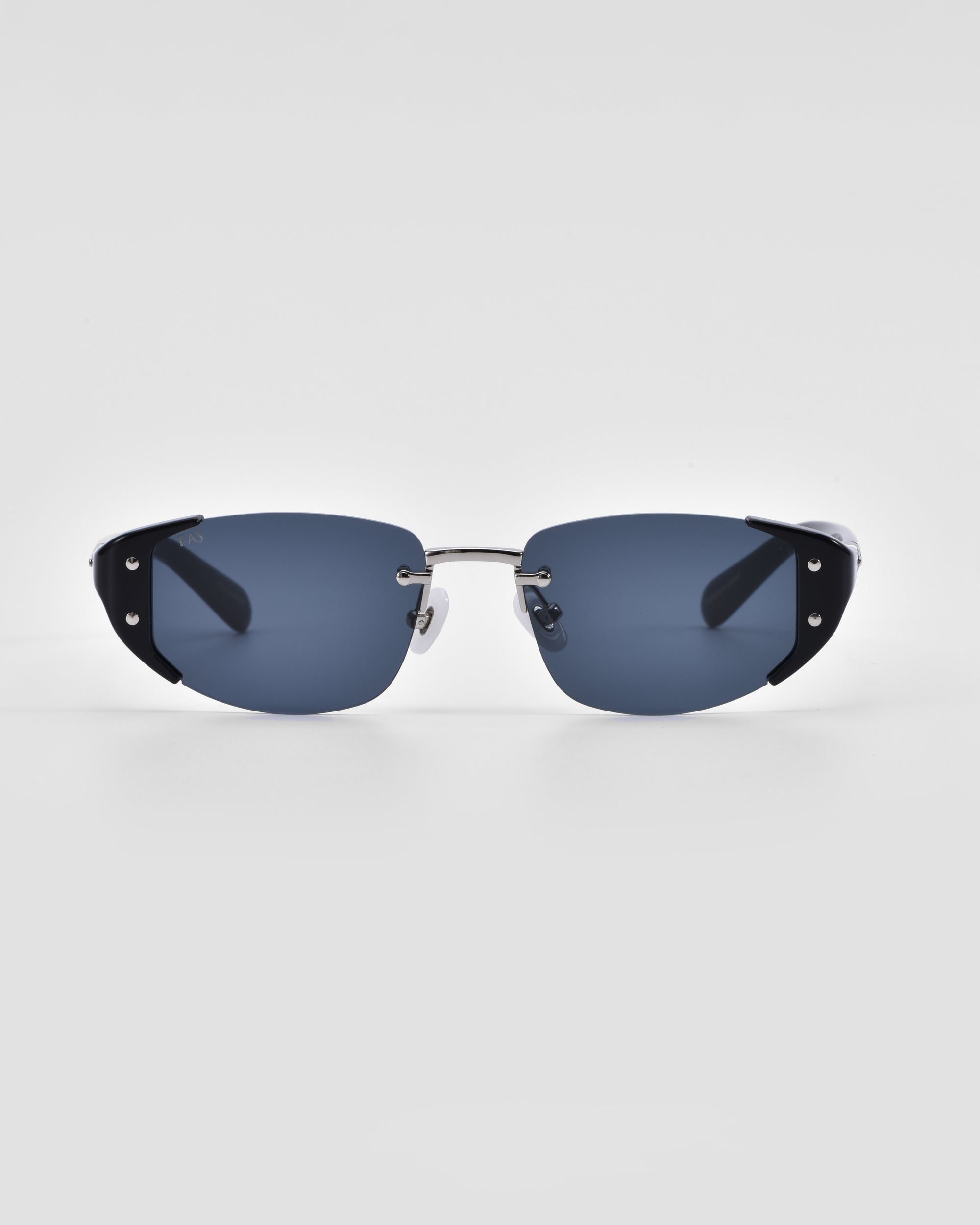 A pair of modern, rimless Harbour sunglasses by For Art&#39;s Sake® with dark blue tinted lenses and thin metallic arms featuring black accents near the hinges. The 18 karat gold plating adds a touch of luxury, while the plain white background emphasizes the sleek design and minimalist style of this retro-inspired eyewear.