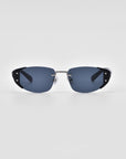 A pair of modern, rimless Harbour sunglasses by For Art's Sake® with dark blue tinted lenses and thin metallic arms featuring black accents near the hinges. The 18 karat gold plating adds a touch of luxury, while the plain white background emphasizes the sleek design and minimalist style of this retro-inspired eyewear.