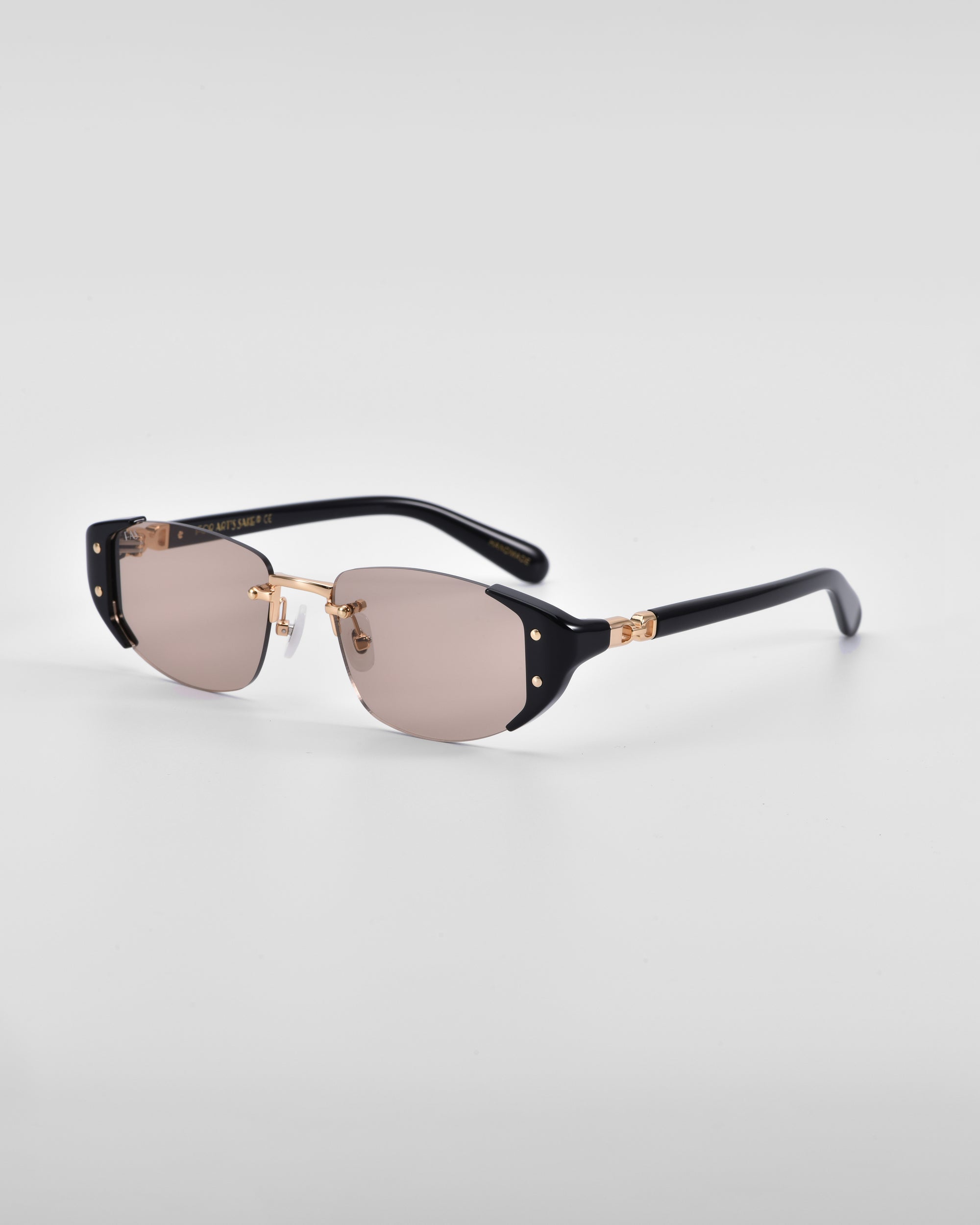 A pair of Harbour sunglasses by For Art&#39;s Sake® with 18 karat gold accents, dark black frames, and slightly tinted lenses. The temples feature retro-inspired gold details near the hinges. Set against a plain white background, these sunglasses highlight a sleek, modern design.