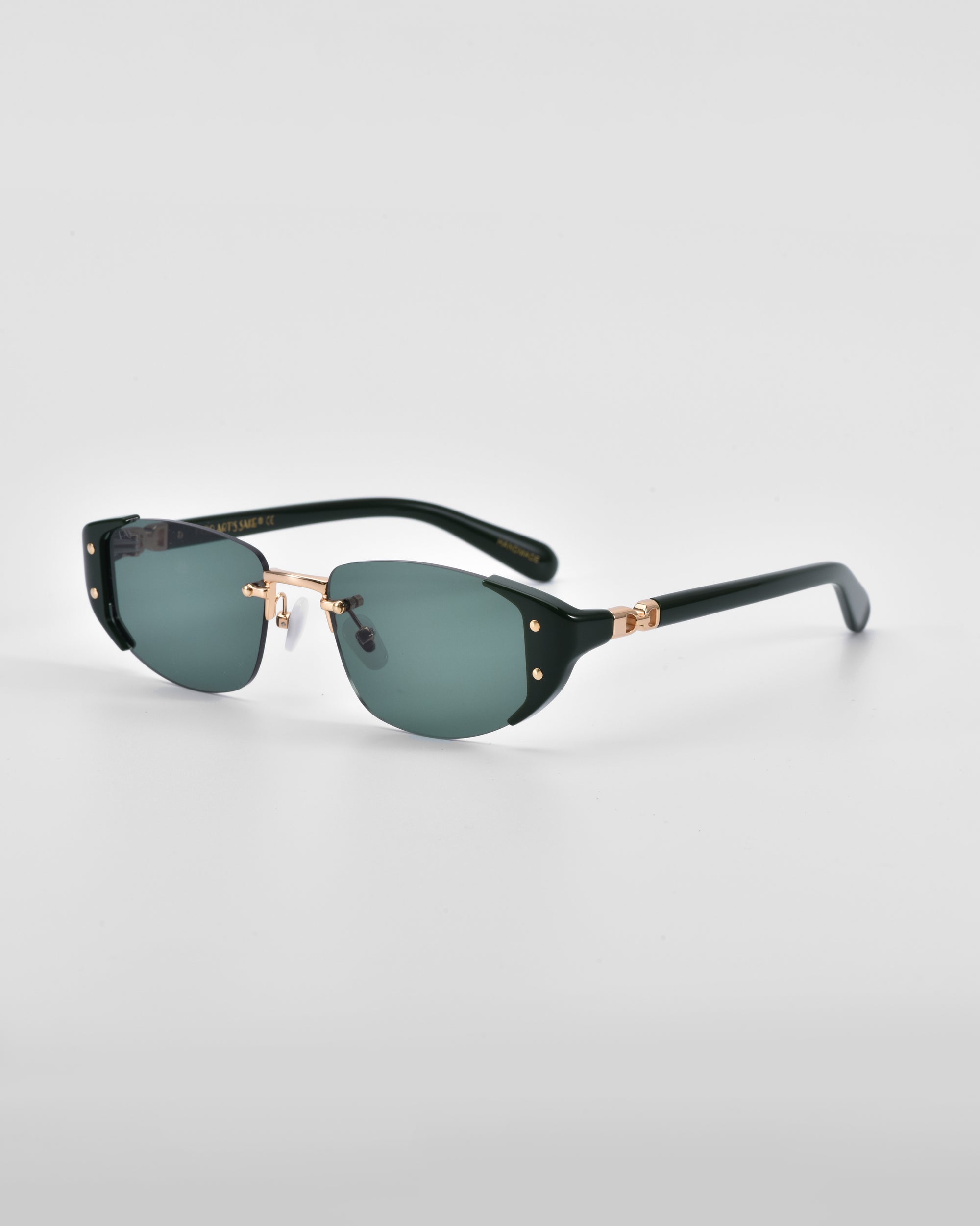 A pair of For Art&#39;s Sake® Harbour sunglasses featuring dark green lenses, black rims, and 18 karat gold plating on the hinges and nose bridge. These retro-inspired sunglasses are set against a plain light gray background.