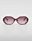 Front view of a pair of Lotus sunglasses by For Art's Sake® with an angular silhouette, featuring tortoiseshell frames and pink-tinted lenses, complemented by jade-stone nose pads. The sunglasses are placed on a plain white background.