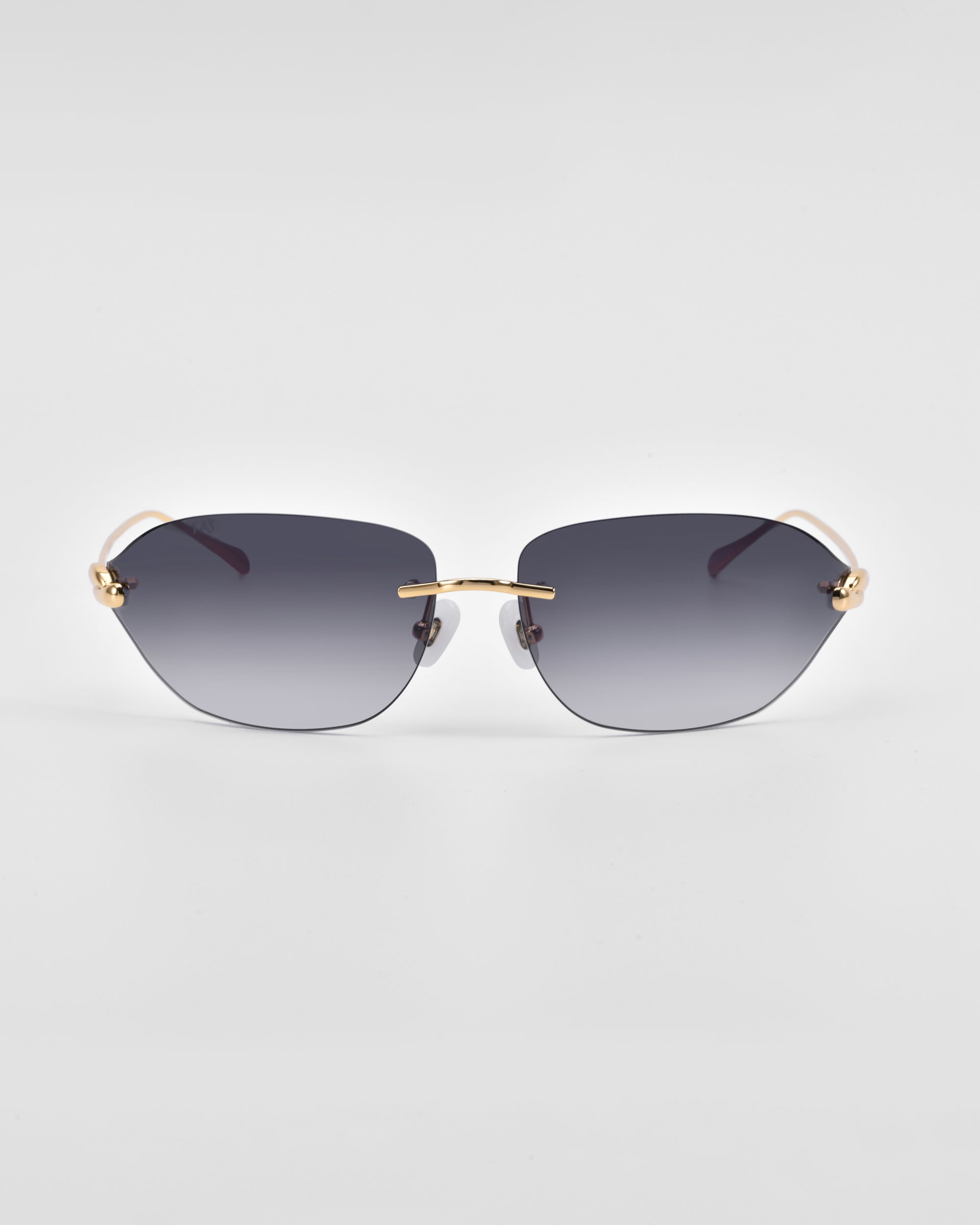 A pair of Serpent I sunglasses with dark gradient lenses and sleek, thin gold frames featuring 18-karat gold plating from For Art&#39;s Sake®. The minimalist design includes a bar across the nose bridge, natural jade-stone nose pads, and curved temples. The background is a clean, plain light grey.