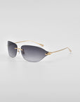 A pair of stylish For Art's Sake® Serpent I rimless sunglasses with dark tinted lenses and golden thin arms, photographed on a white surface. The minimalistic design, featuring 18-karat gold plating, gives them a sleek, modern look.