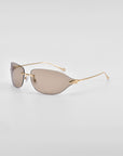 A pair of Serpent I sunglasses by For Art's Sake® with light brown-tinted frameless wrap lenses and thin, gold-colored wire temples. The sleek and minimalist design gives them a modern and sophisticated look, enhanced by the luxurious 18-karat gold plating on the temples, set against a plain white background.