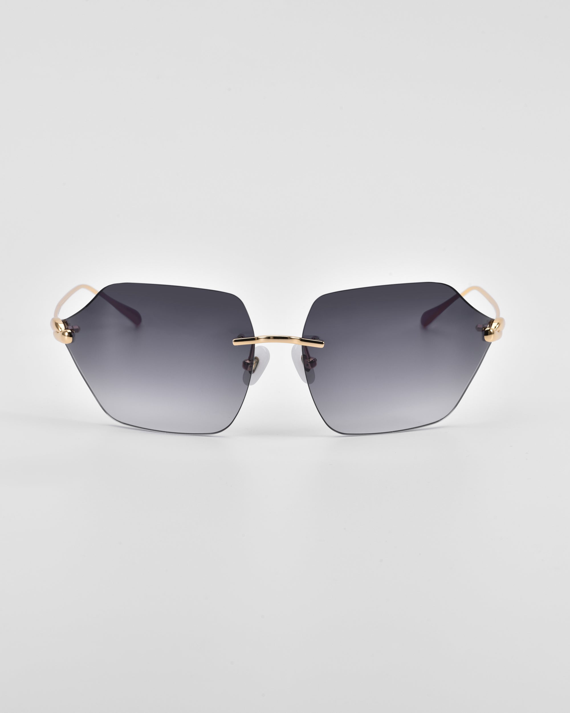 A pair of stylish For Art&#39;s Sake® Serpent II sunglasses featuring oversized, geometric hexagonal lenses with dark gray gradient tint and 18-karat gold-plated metal accents on the hinges and nose bridge, set against a plain white background.