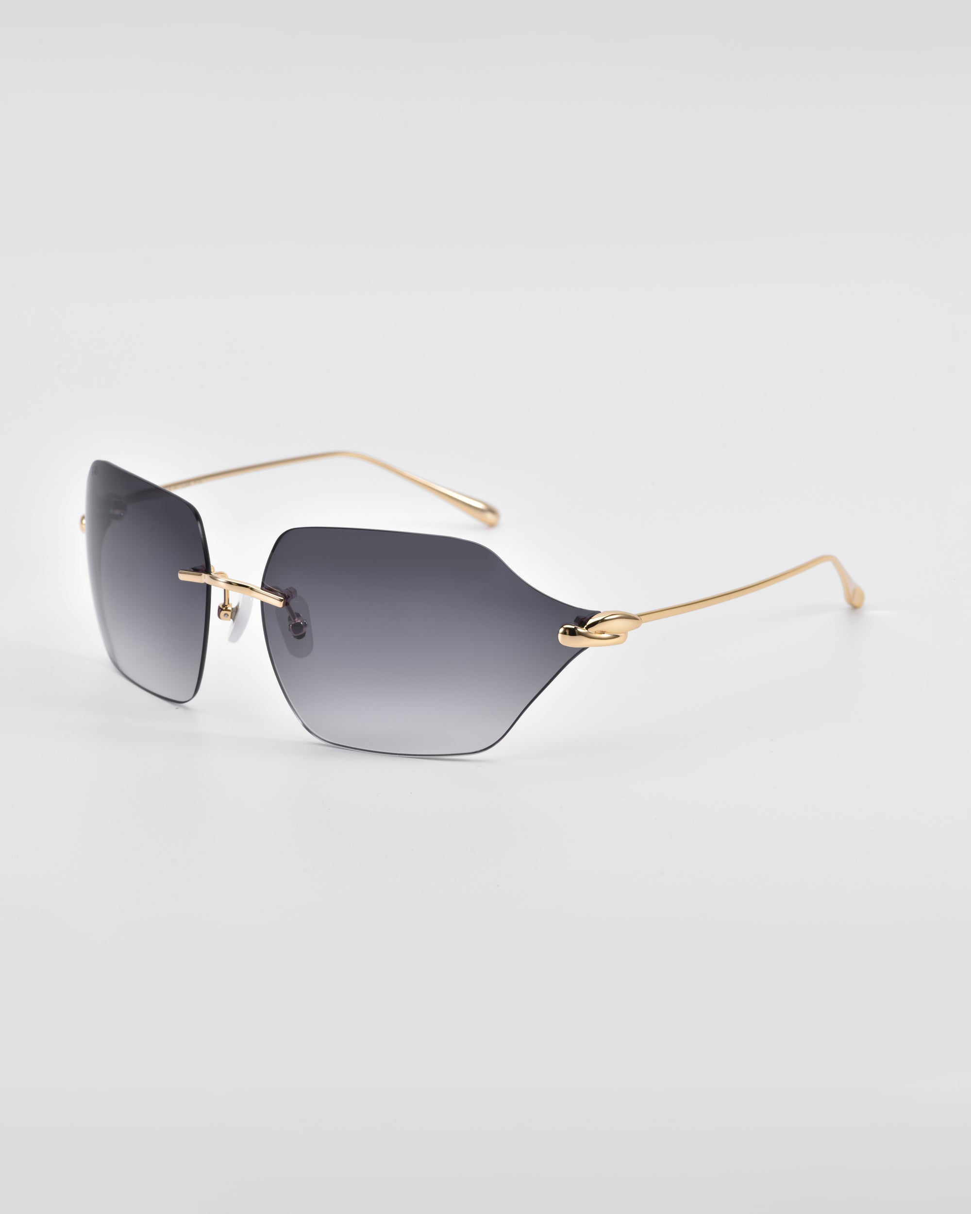 A pair of sleek, modern For Art&#39;s Sake® Serpent II sunglasses with grey gradient lens and thin gold temples shown on a plain white background. The design features rimless lenses with a slight cat-eye shape, 18-karat gold plating, and minimalistic yet stylish metal accents.
