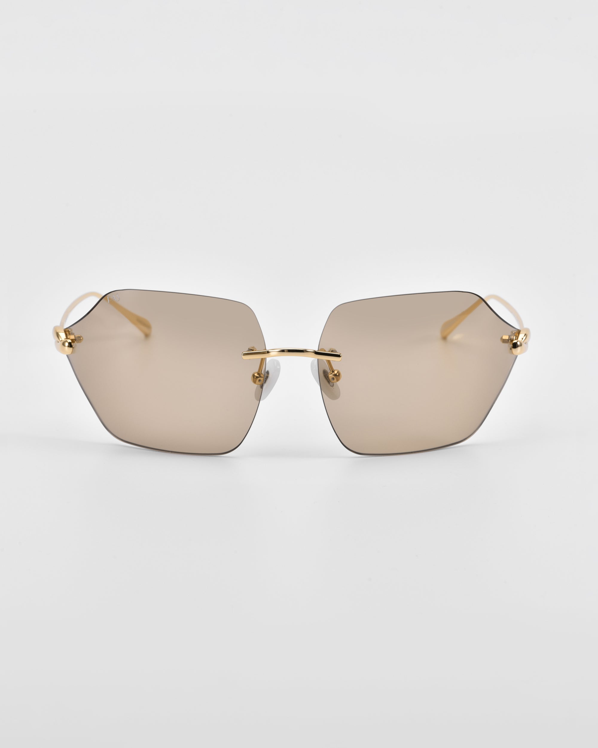 A pair of stylish Serpent II sunglasses from For Art&#39;s Sake® features a frameless wrap lens design with slightly tinted, polygonal lenses and thin, golden arms. Displayed against a plain white background, the nose bridge also boasts 18-karat gold plating, accentuating the modern design of the eyewear.
