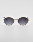 A pair of stylish Sky sunglasses by For Art's Sake® with round, dark-tinted lenses and a golden metal frame. Featuring 18-karat gold detailing and sleek, minimalist design accents, the glasses come with natural jade-stone nose pads, set against a plain white background.