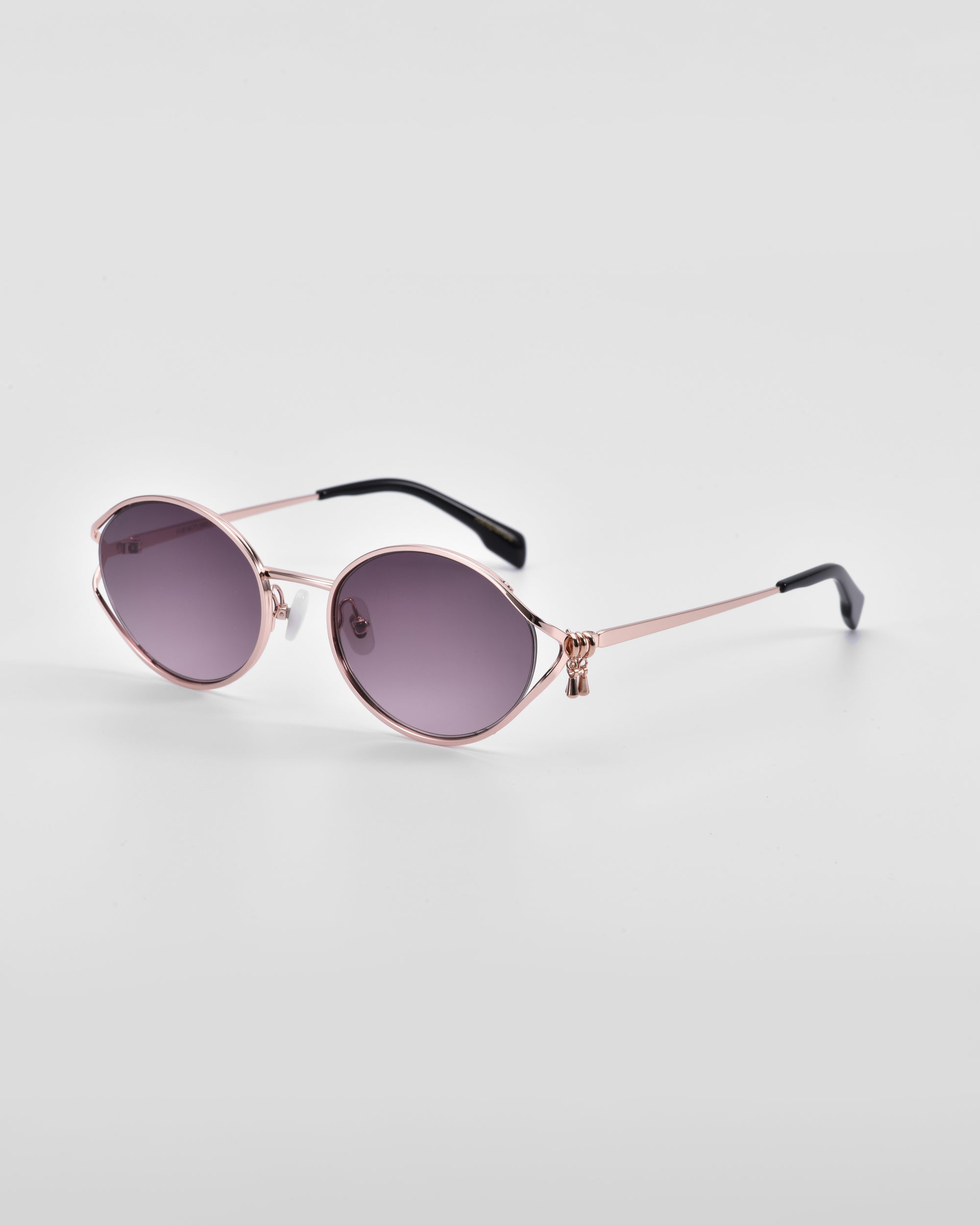 A pair of stylish Sky sunglasses from For Art&#39;s Sake® with rose gold frames and dark, tinted lenses. The sunglasses feature 18-karat gold thin arms with black tips and natural jade-stone nose pads. The overall design is elegant and modern against a plain white background.