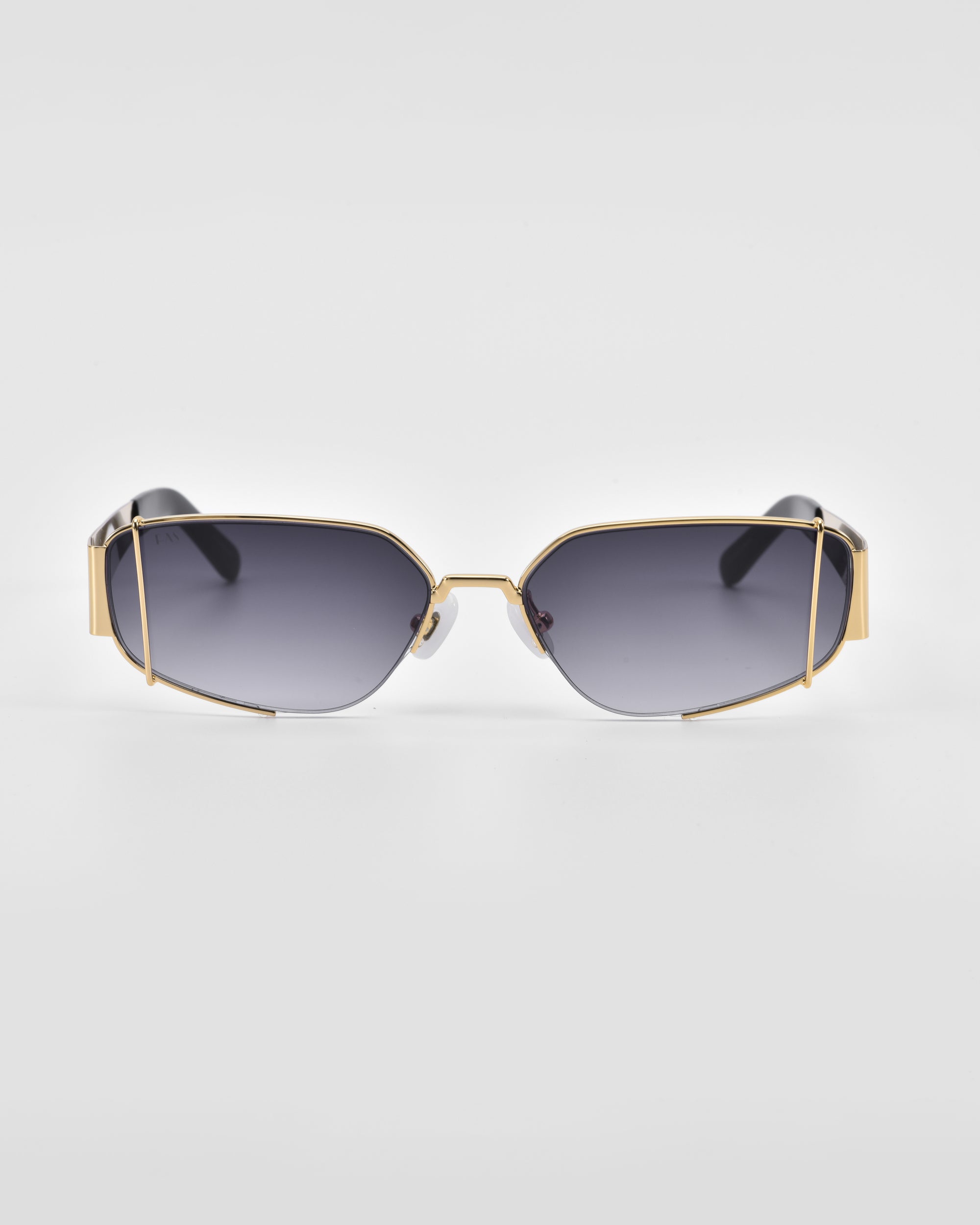 Gold-trimmed, rectangular sunglasses with dark gradient lenses against a white background. *Talia* by *For Art&#39;s Sake®* features 18-karat gold frames with unique angular design accents on the top corners and a delicate nose bridge. The temples are thick and blend into black tips.
