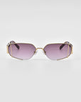 A pair of For Art's Sake® Talia sunglasses with purple-tinted lenses and a unique geometric metal frame. The frame, finished in 18-karat gold, features an angular design, giving the sunglasses a modern and edgy look. The background is plain white.