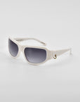 A pair of **Raven** wrap sunglasses with dark tinted lenses. The white frames have a sleek, modern design and feature a small 18-karat gold ring detail on the temples. The **For Art's Sake®** sunglasses are set against a plain white background.