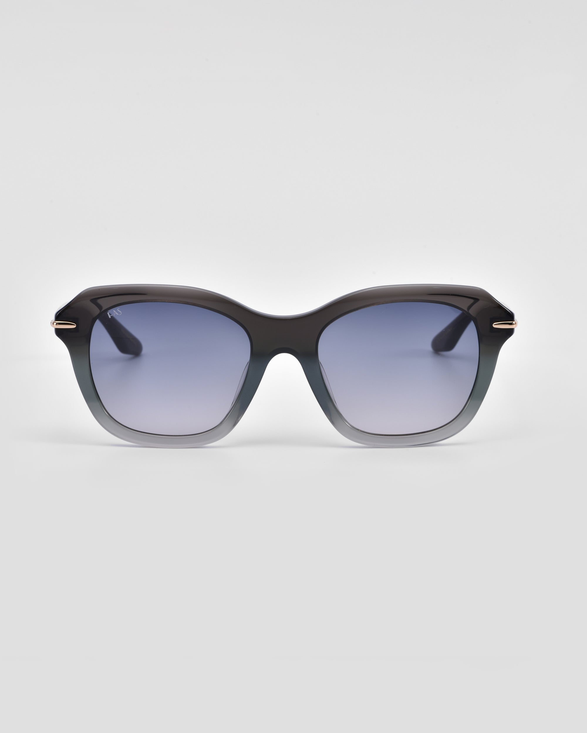 A pair of stylish, oversized For Art&#39;s Sake® Helene cat-eye sunglasses with black frames that gradually transition to a lighter shade at the bottom. The lenses are tinted dark, providing a cool and fashionable look. The background is plain and light gray.