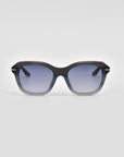 A pair of stylish, oversized For Art's Sake® Helene cat-eye sunglasses with black frames that gradually transition to a lighter shade at the bottom. The lenses are tinted dark, providing a cool and fashionable look. The background is plain and light gray.