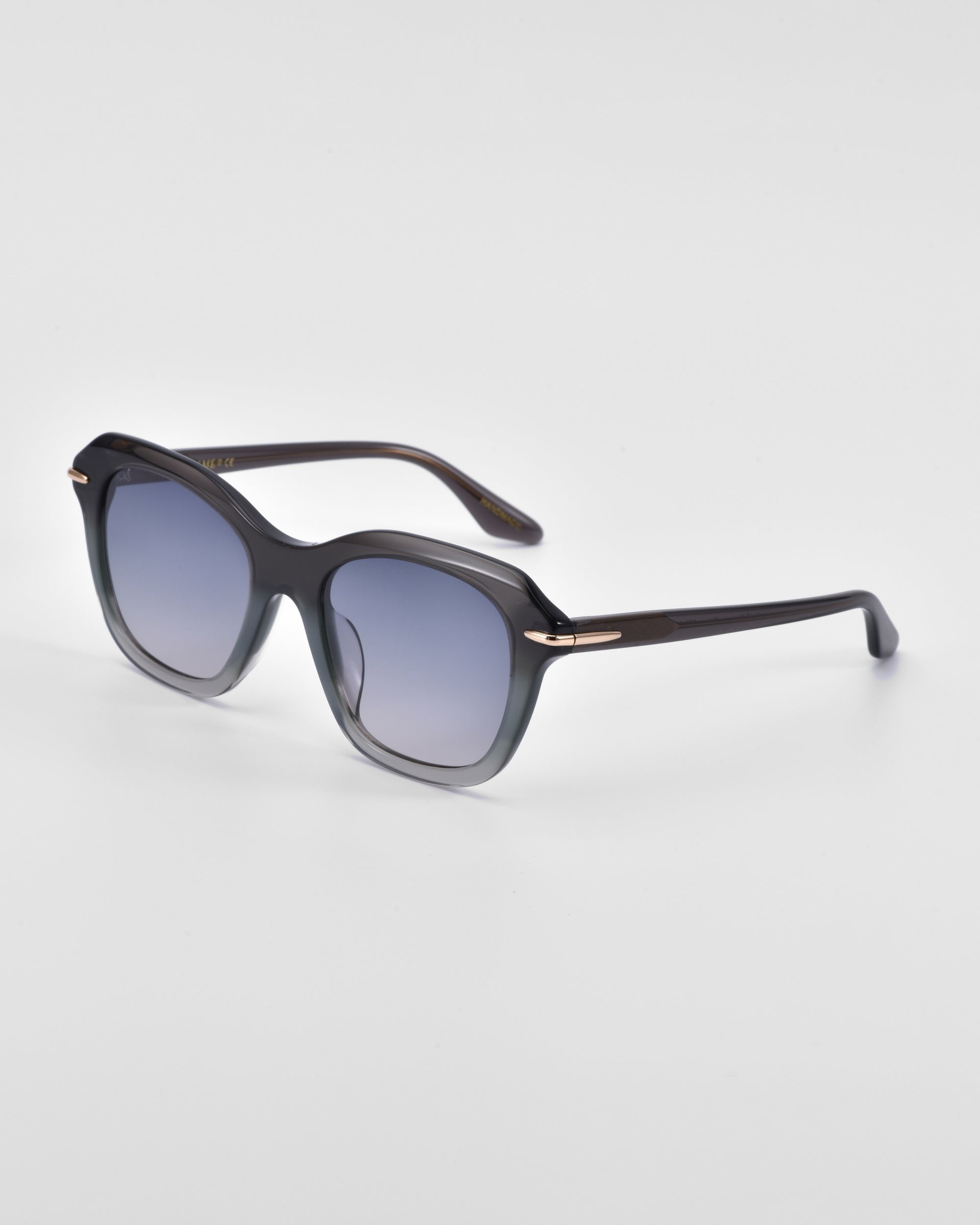 A pair of stylish Helene sunglasses by For Art&#39;s Sake® featuring large, square-shaped dark lenses and sleek, dark frames with a subtle metallic accent on the temples. The Helene sunglasses by For Art&#39;s Sake® are angled slightly to showcase both the front and side profiles against a plain white background, making them a true statement piece.