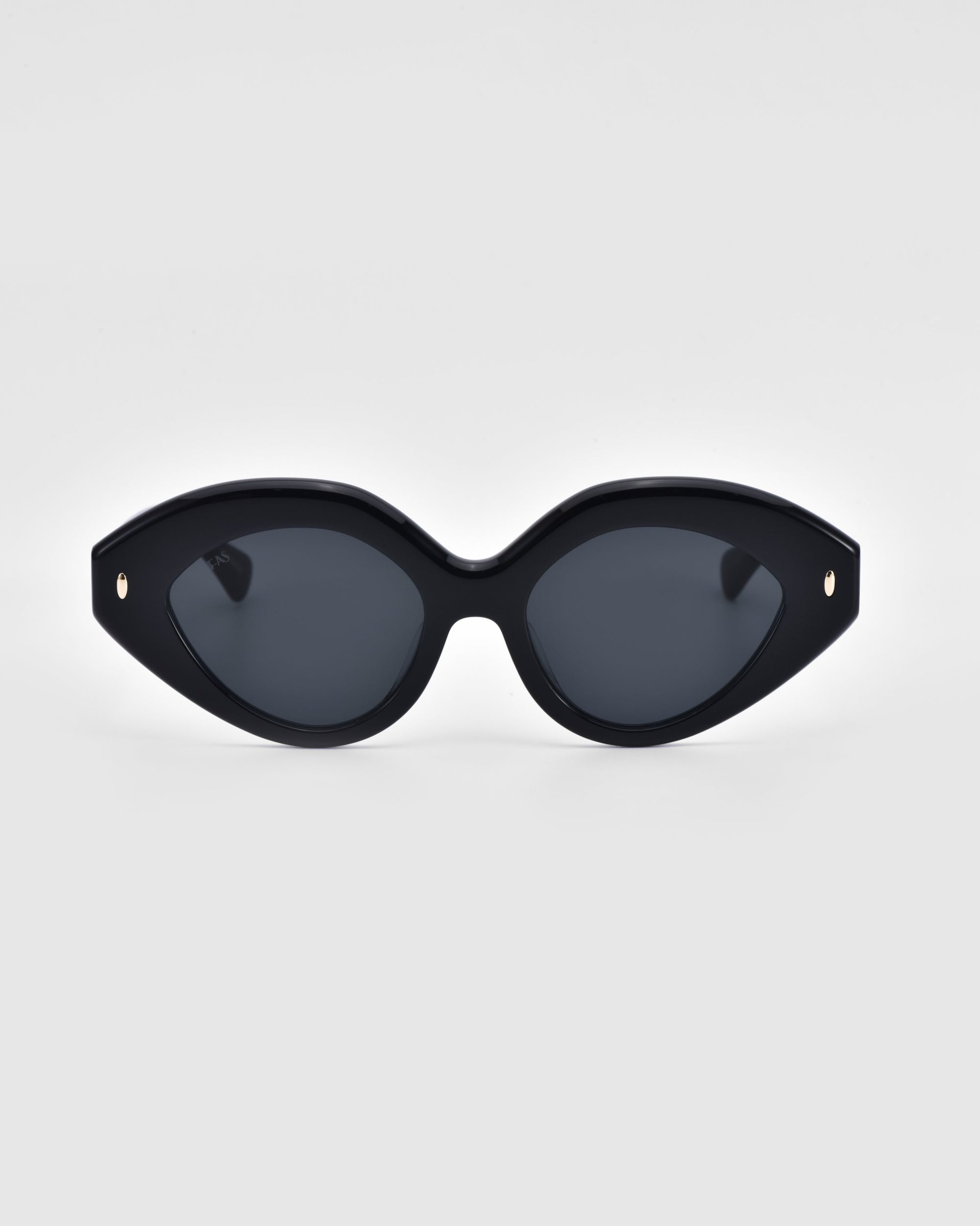 A pair of stylish Vera cat-eye sunglasses from For Art's Sake®, featuring dark tinted lenses, is displayed against a plain white background. The eco-friendly sunglasses boast a glossy finish with small metallic details at the corners of the frame.